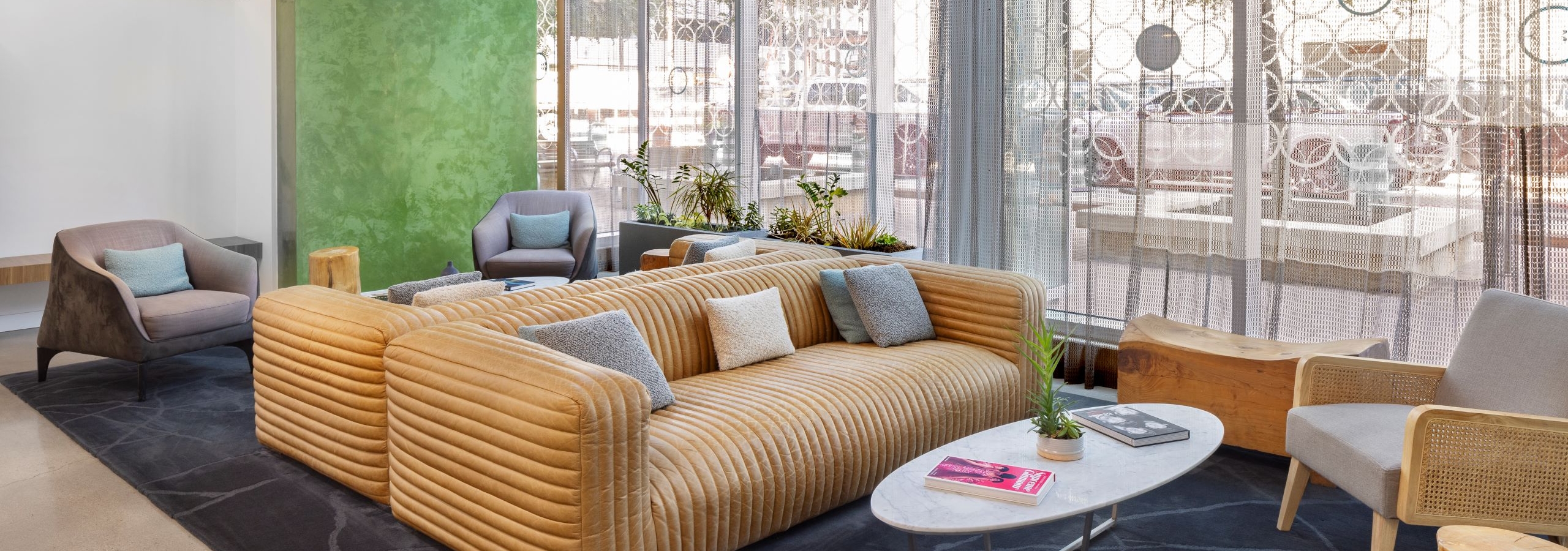 AMLI on 2nd lobby with floor to ceiling windows and green wall with gold sofas and a few chairs around coffee table