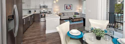 AMLI Piedmont Heights kitchen with a round table with four chairs and dark floors with island and stainless steel appliances
