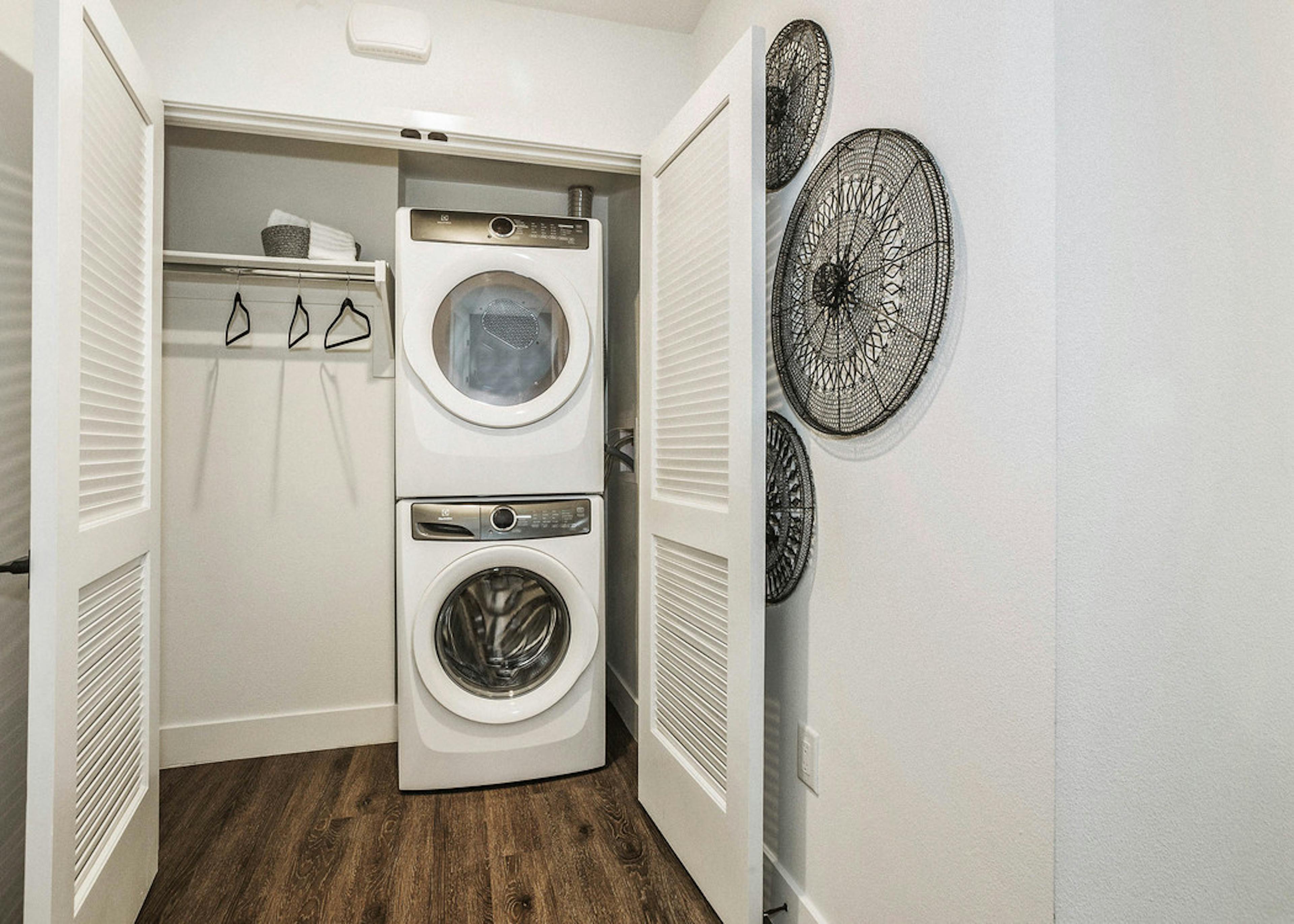 View of full sized front loading stacked washer and dryer closet with laundry hanging rod at AMLI Marina Del Rey apartments