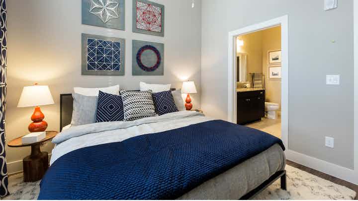 Interior view of AMLI Campion Trail bedroom area with bed with dark blue sheets and pillows and night stand