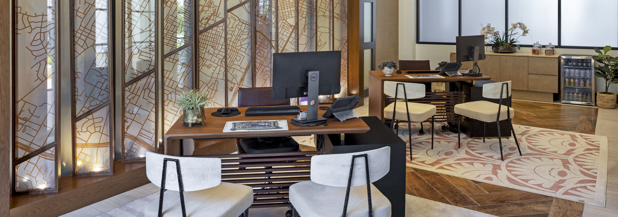AMLI Lakeline leasing office with wood desks and white upholstered chairs and patterned rugs next to glass window display