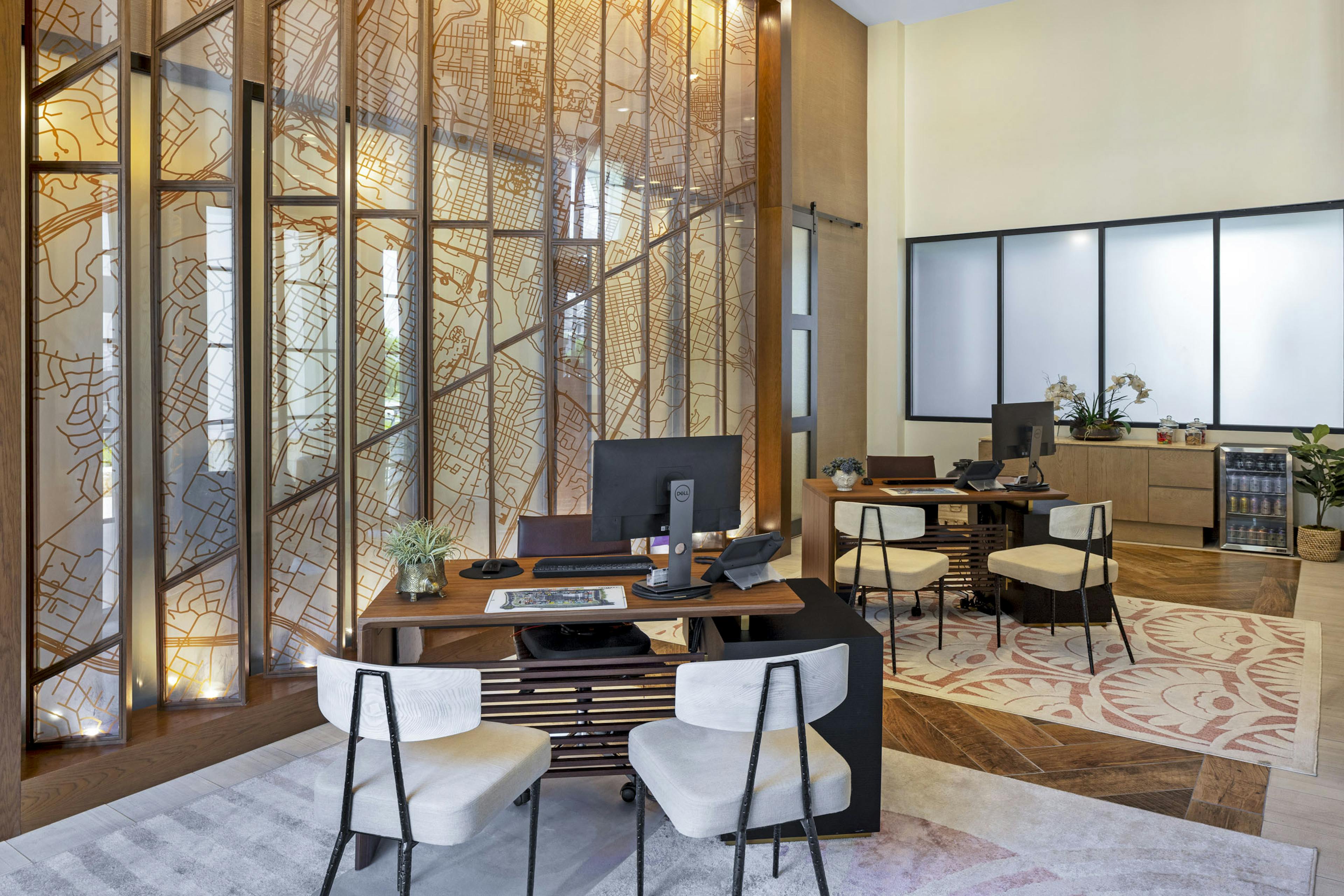 AMLI Lakeline leasing office with wood desks and white upholstered chairs and patterned rugs next to glass window display