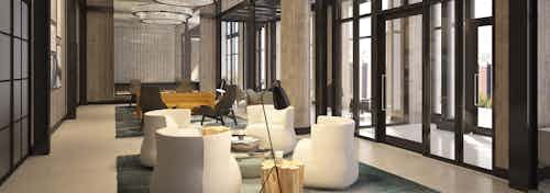 Lobby of AMLI 808 apartments with 4 white club chairs on area rug with chandeliers above and large glass doors and windows
