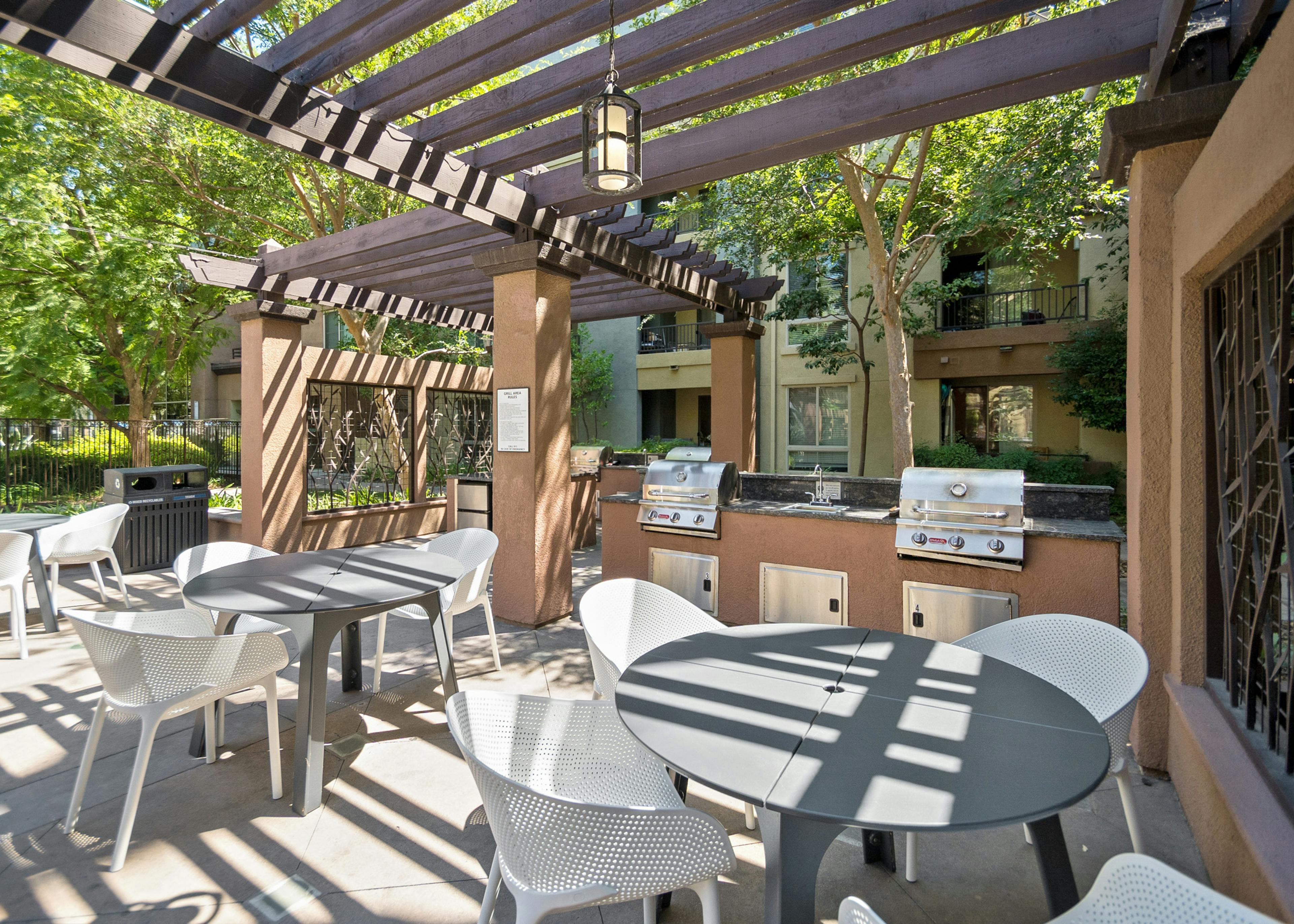 Pergola shade canopy over spacious outdoor grilling station with three dining tables at AMLI Warner Center apartment building