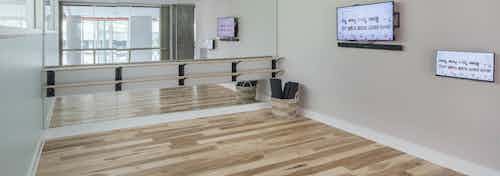 Yoga studio at AMLI Arts Center with a large wall mirror and flat screen TV with smooth wood flooring and open space