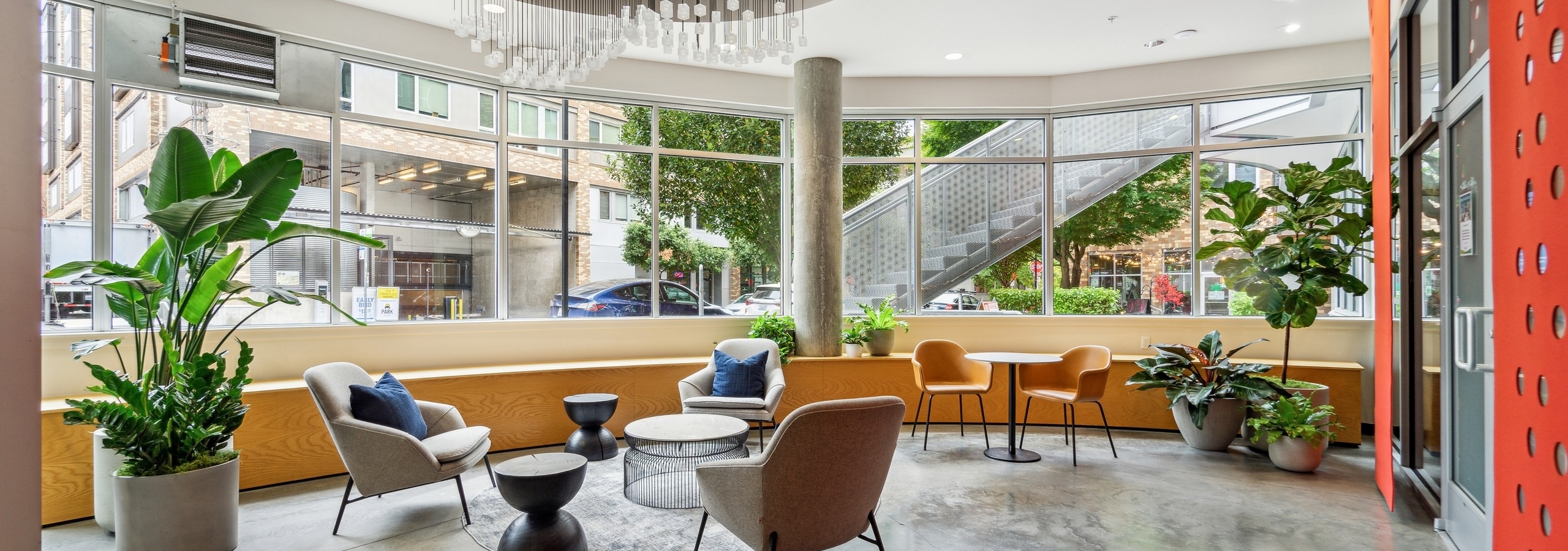 AMLI South Lake Union lobby with cement flooring and multiple chairs and plants and a wall of windows and a large chandelier
