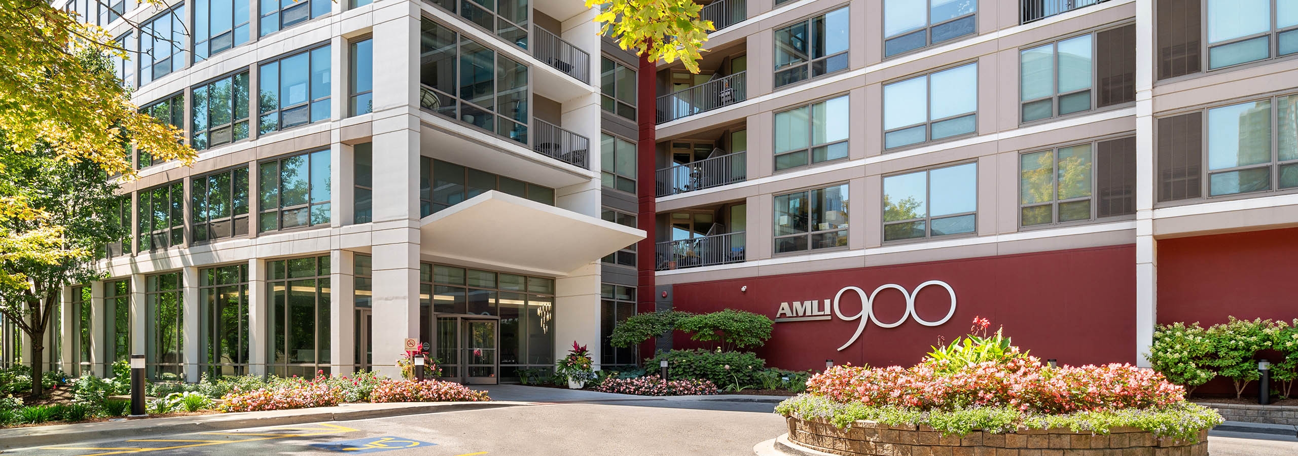 Daytime view of AMLI 900 high rise building exterior with floor to ceiling windows in each apartment and lively landscaping