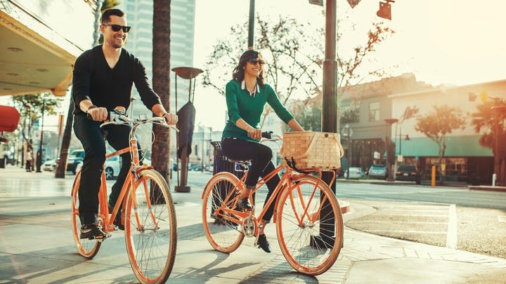 A Man and women on bicycles riding through the city on a beautiful sunny day at dusk on main street in Bellevue
