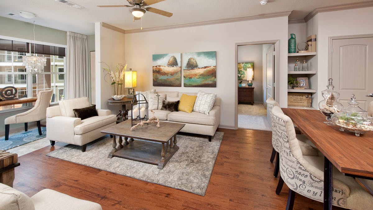 Living room at AMLI North Point with a large window and chestnut colored wood floors with neutral, elegant decor