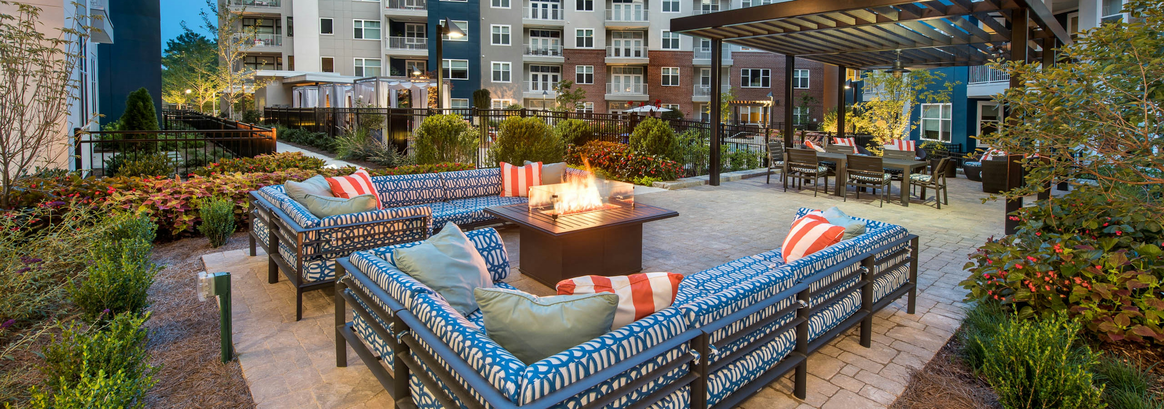 Two patterned blue L couches with a fire pit in the center and green foliage surrounding the patio area at AMLI Buckhead