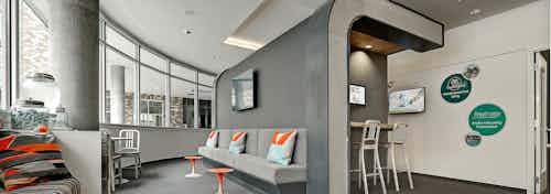 The leasing office at AMLI South Lake Union with high ceilings, seating and a beverage station with bright art work and tv on the wall