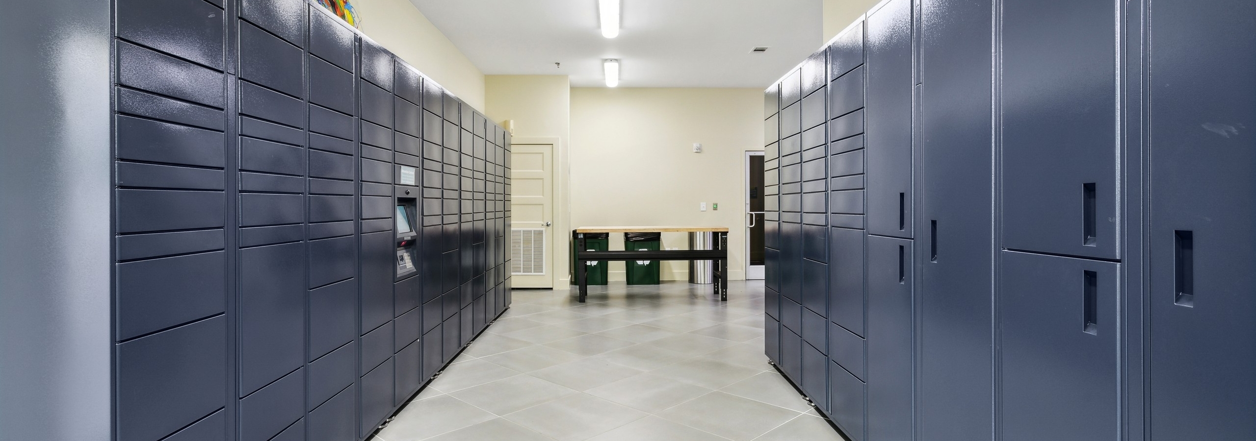 Package room at AMLI Buckhead apartments with two parallel full walls of blue Amazon lockers with light gray tile floor