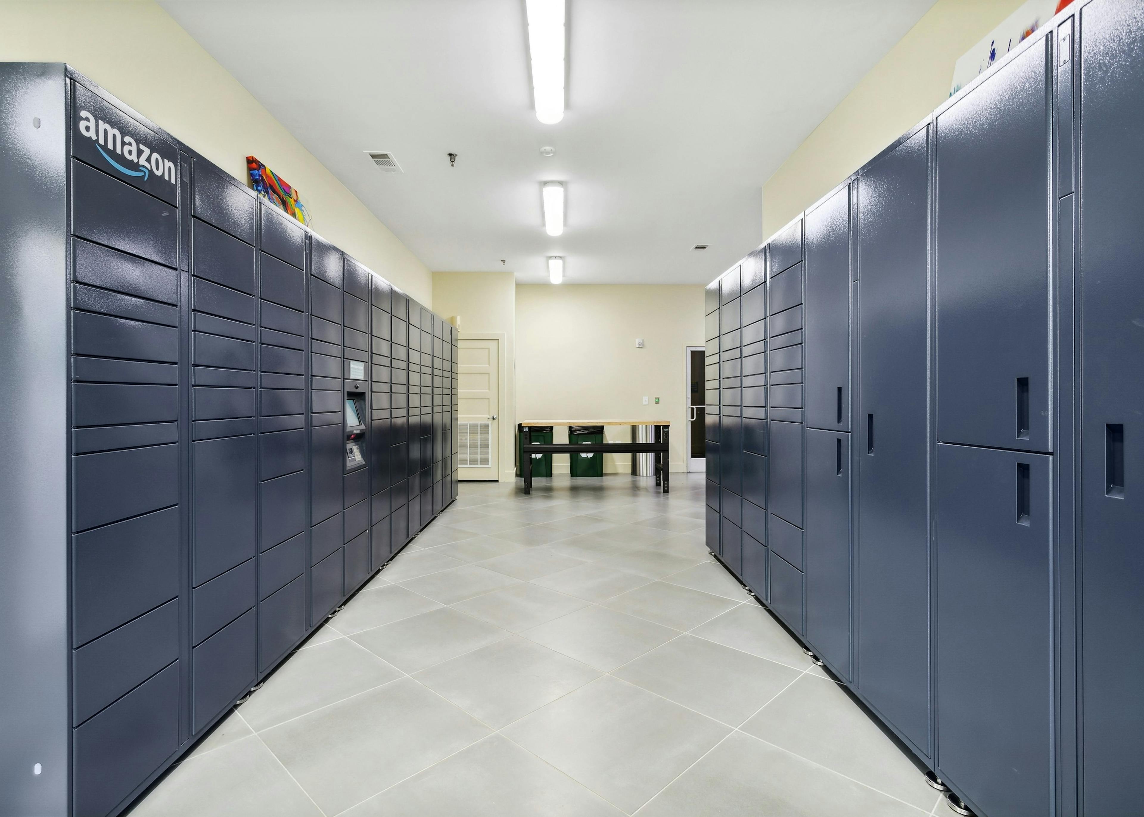 Package room at AMLI Buckhead apartments with two parallel full walls of blue Amazon lockers with light gray tile floor 