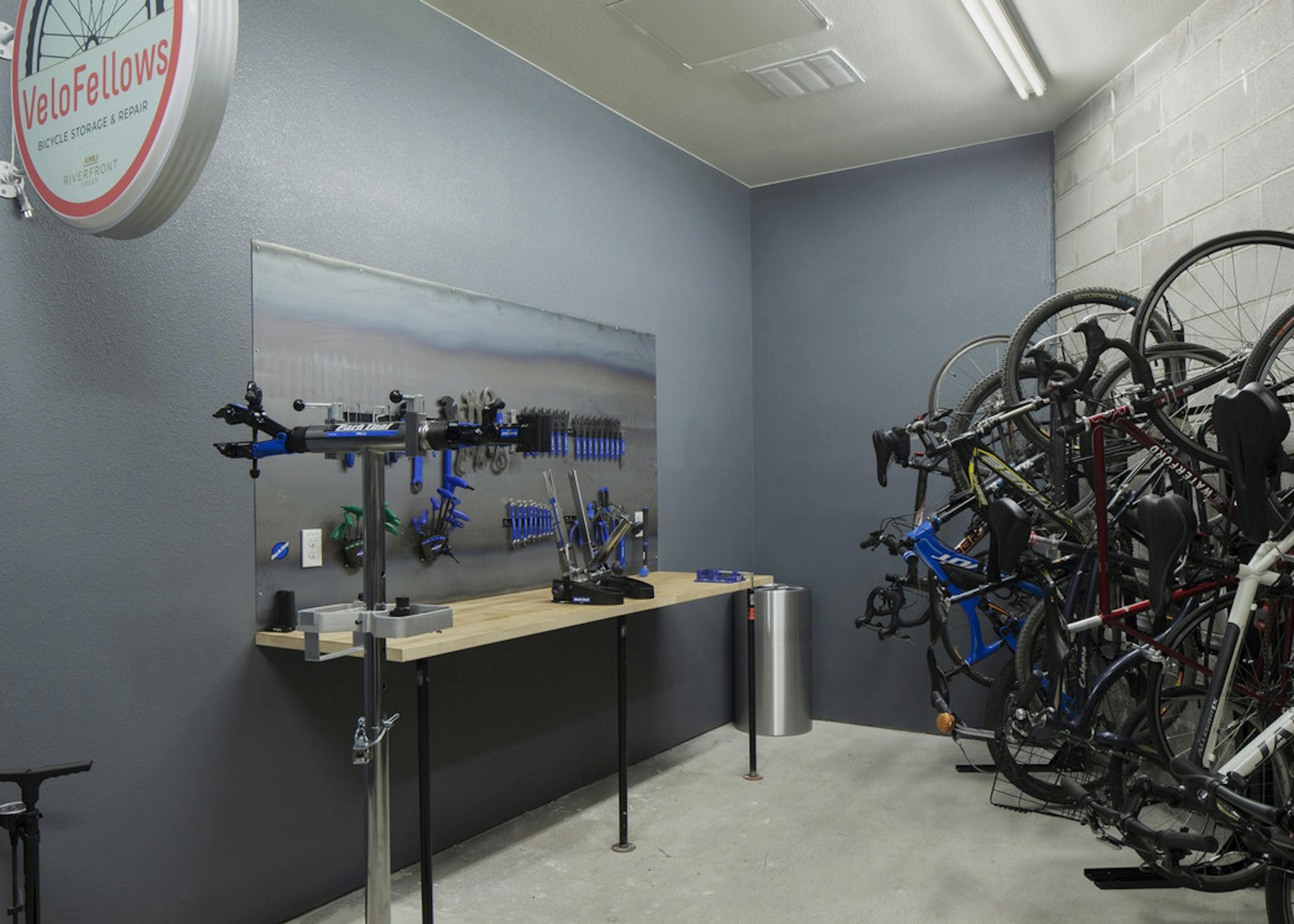 Interior bike repair room area at AMLI Riverfront Green apartments with view of work station table with tools and bike racks 