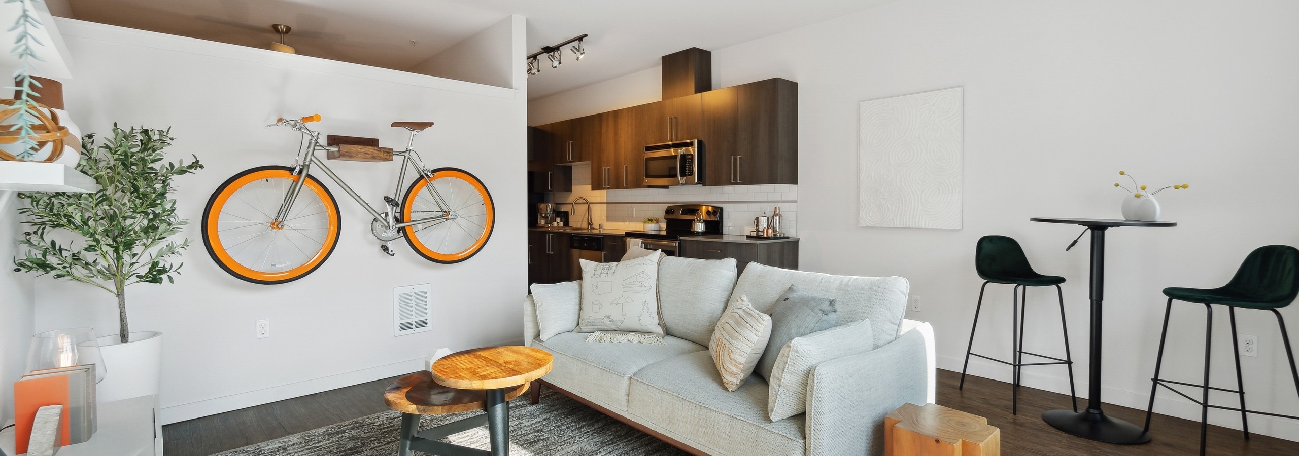AMLI South Lake Union living room with an orange bicycle mounted on white wall and dining table and a view into the kitchen