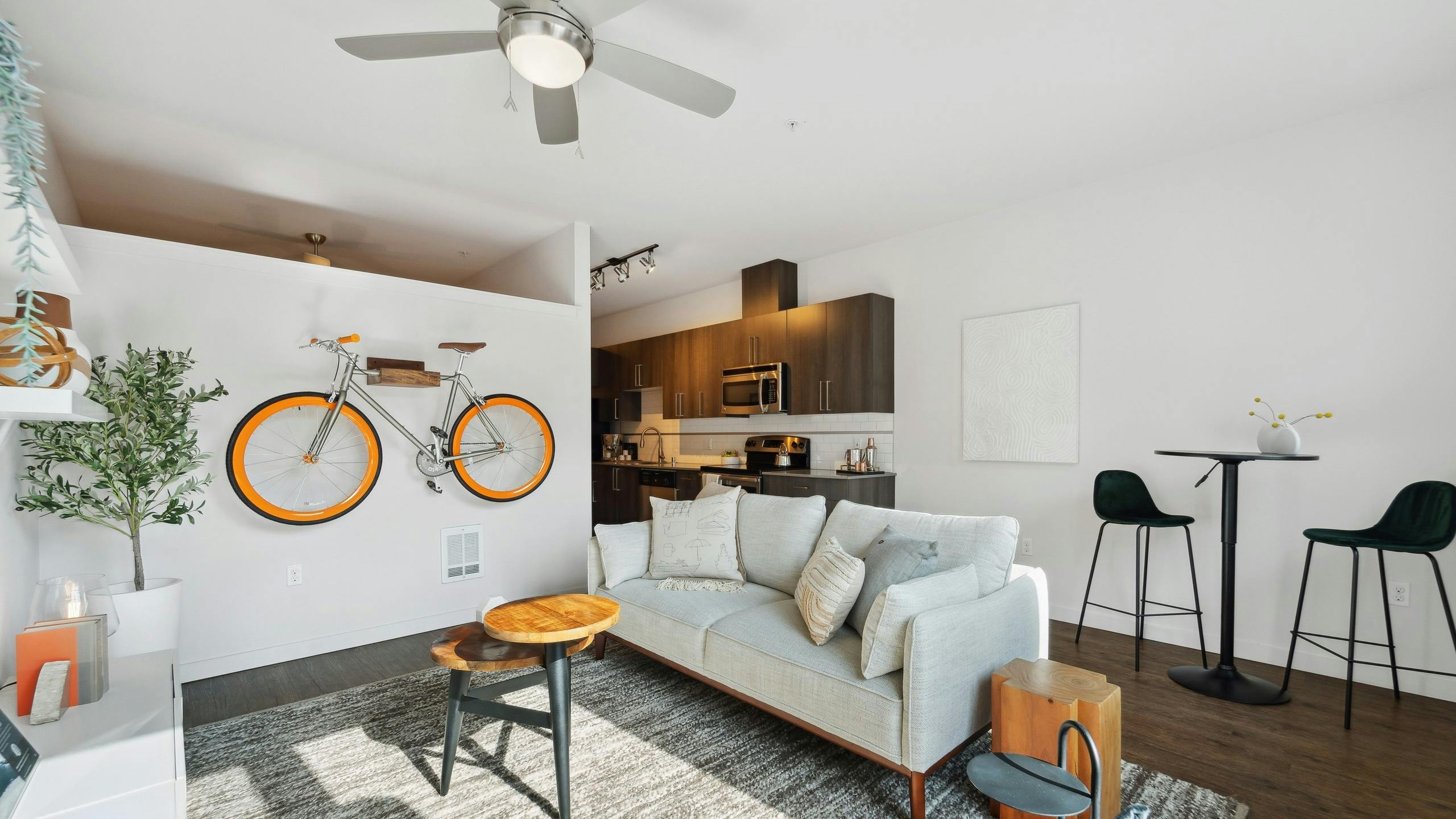 AMLI South Lake Union living room with an orange bicycle mounted on white wall and dining table and a view into the kitchen