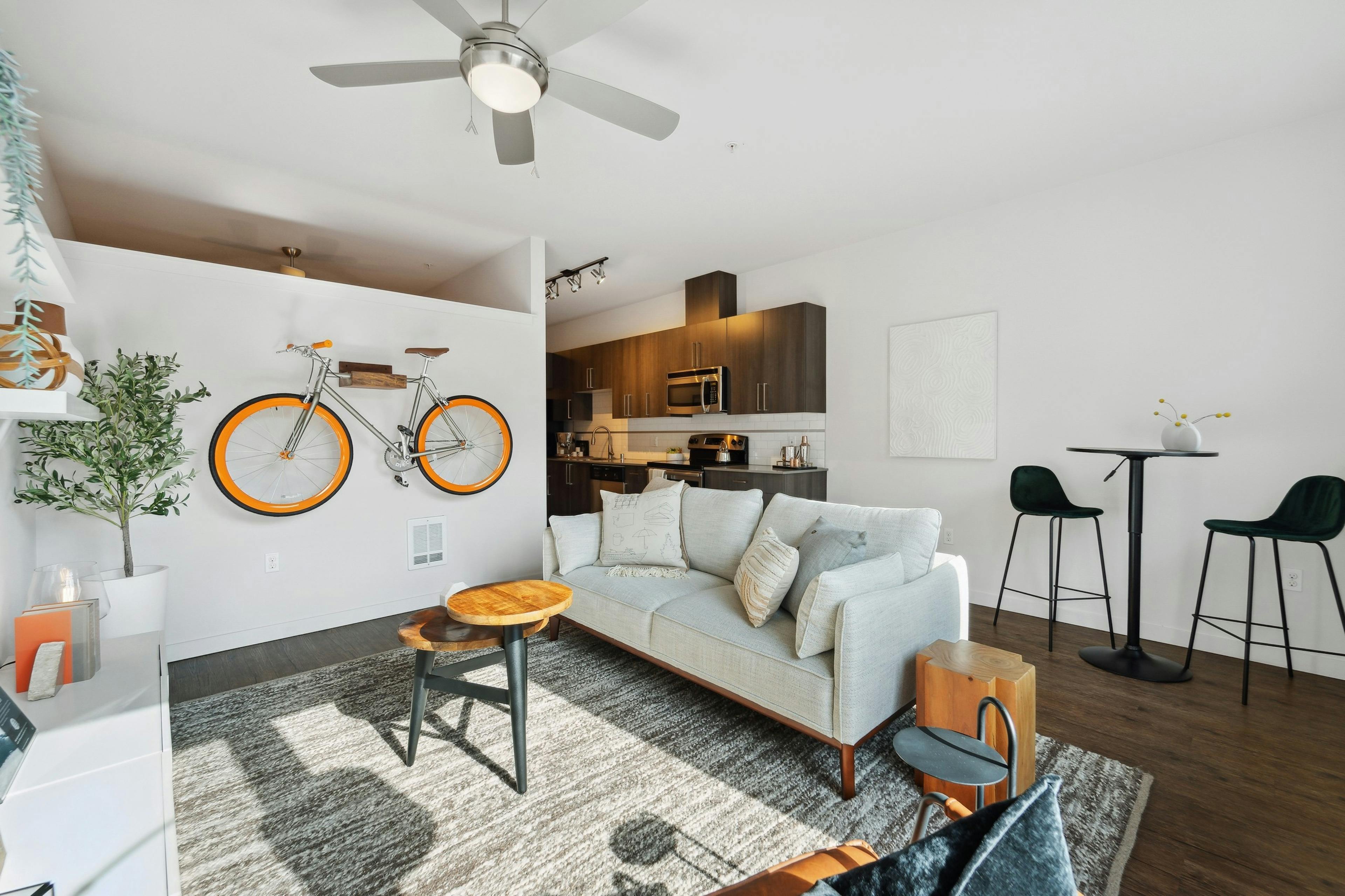 AMLI South Lake Union living room with an orange bicycle mounted on white wall and dining table and a view into the kitchen