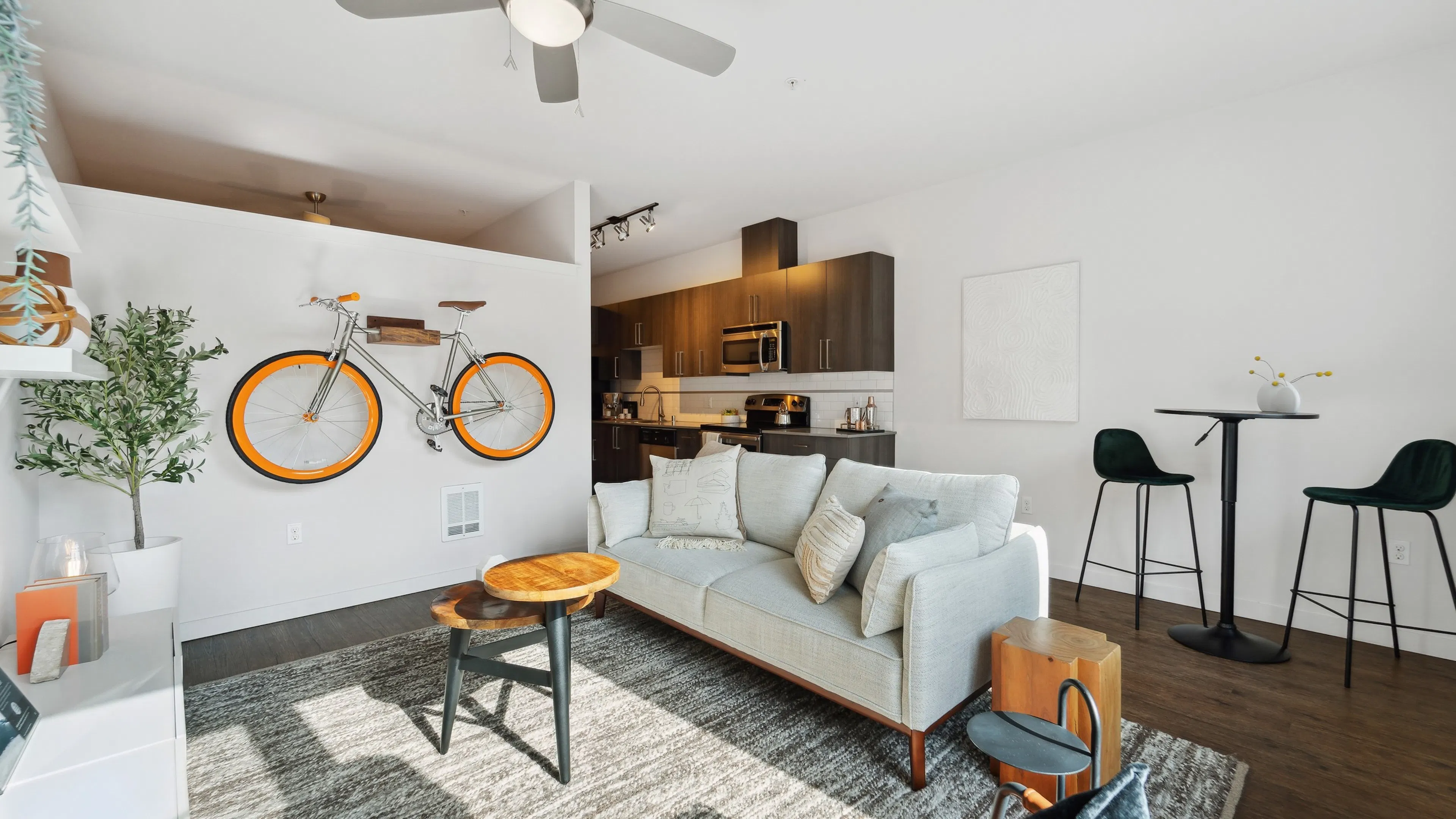 AMLI South Lake Union living room with an orange bicycle mounted on white wall and dining table and a view into the kitchen