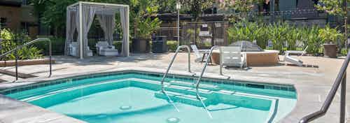 Daytime view of heated spa at AMLI Warner Center apartments with private cabana and fire pit with chairs in the background