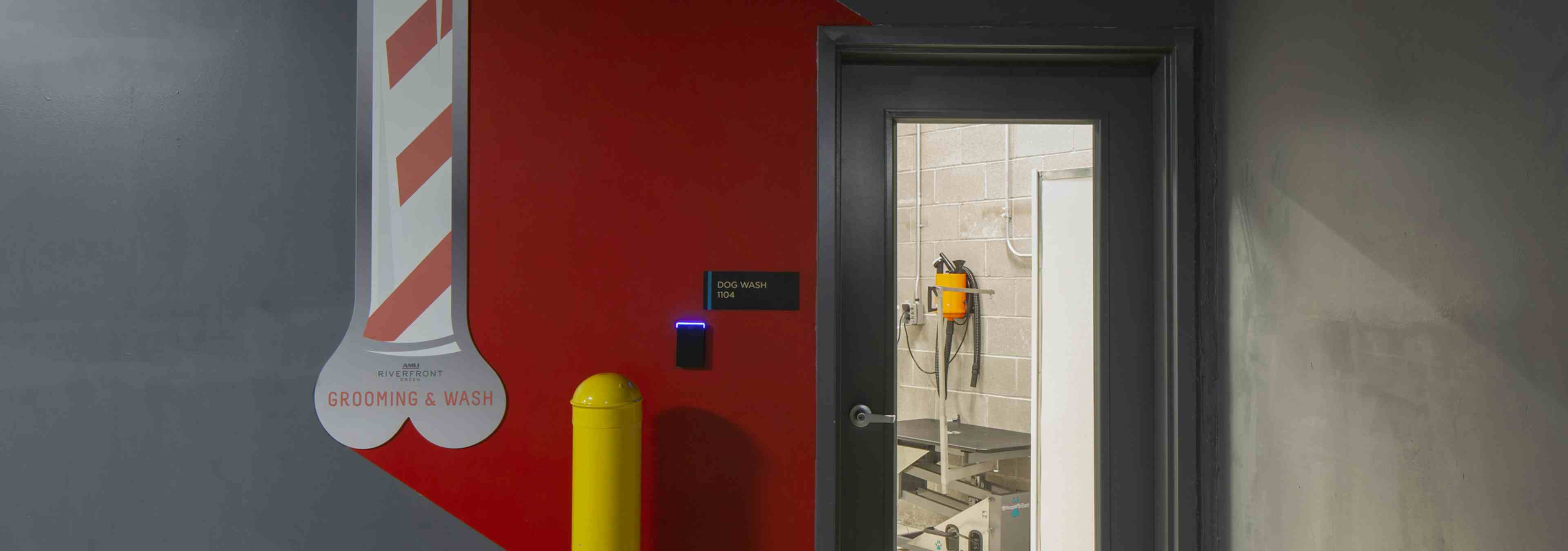 Pet washing area at AMLI Riverfront Green apartments with view of glass entry door with view of dryer and Paw wash signage