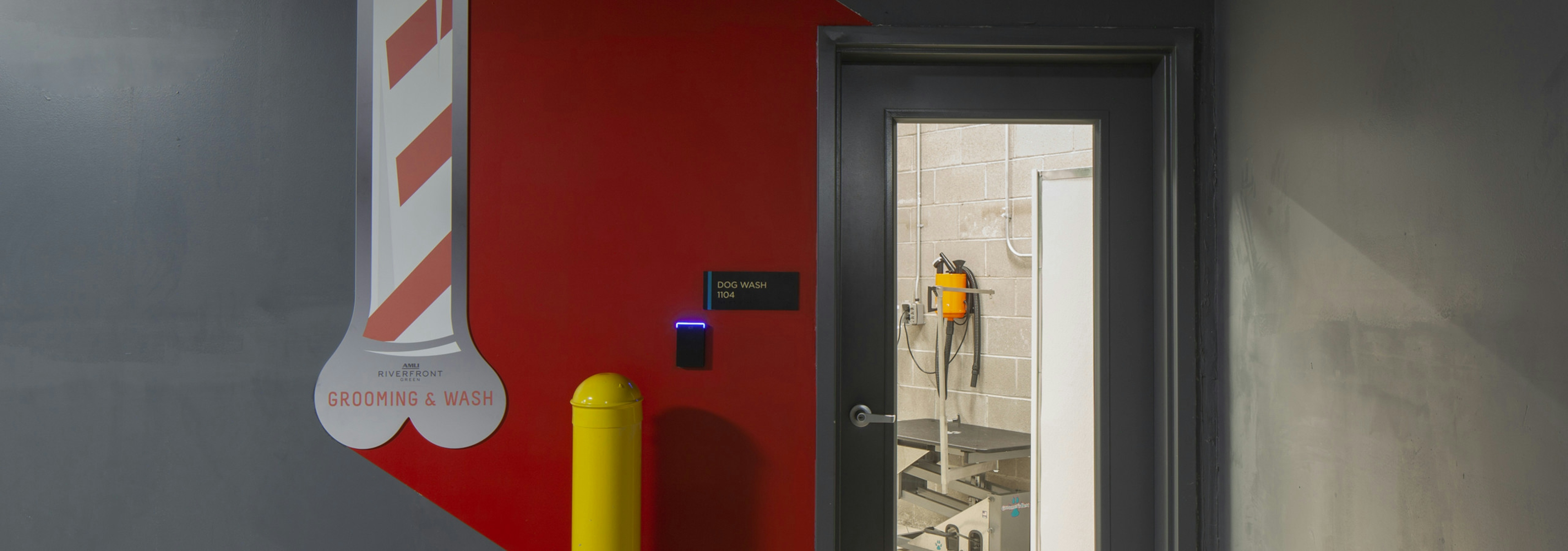 Pet washing area at AMLI Riverfront Green apartments with view of glass entry door with view of dryer and Paw wash signage