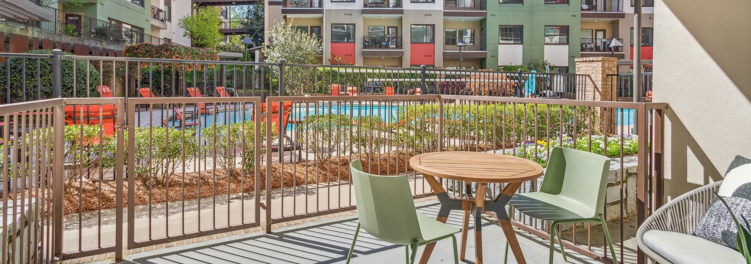 Exterior view of spacious furnished patio overlooking colorful building courtyard with a pool at AMLI Ponce Park apartments