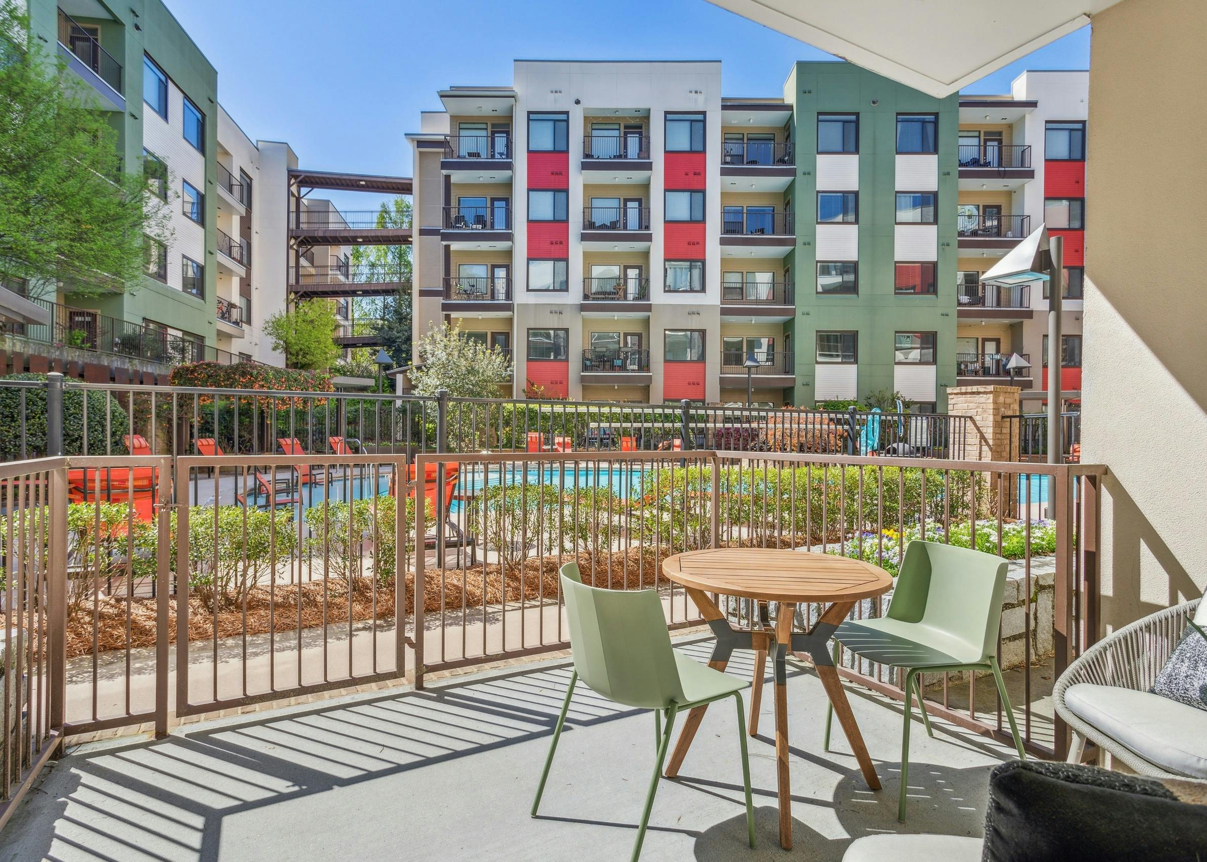 Exterior view of spacious furnished patio overlooking colorful building courtyard with a pool at AMLI Ponce Park apartments