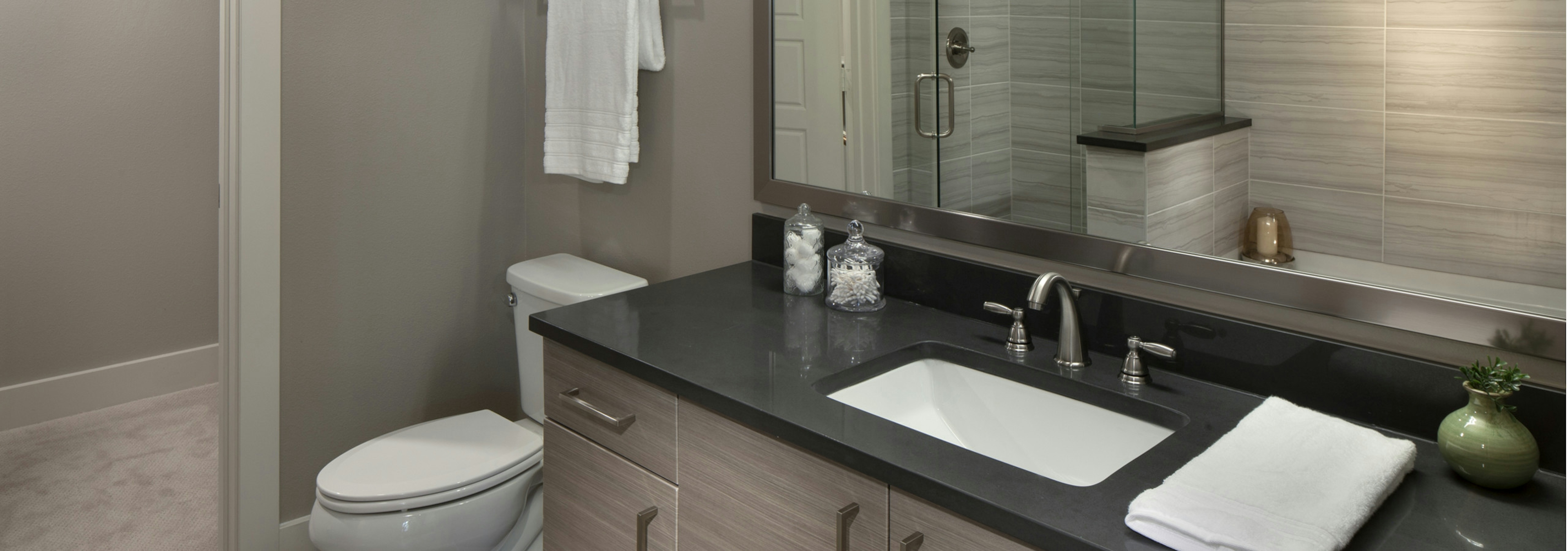 A bathroom in an apartment at AMLI Riverfront Green with view of toilet and large mirror with shower in the reflection