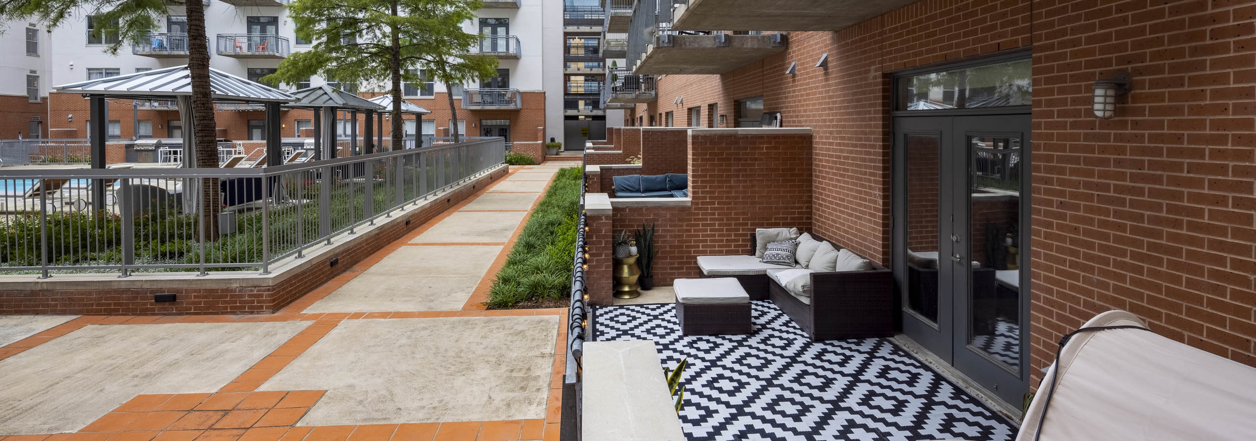 Large outdoor poolside apartment patio at AMLI Downtown with a black and white carpet and outdoor lounging furniture