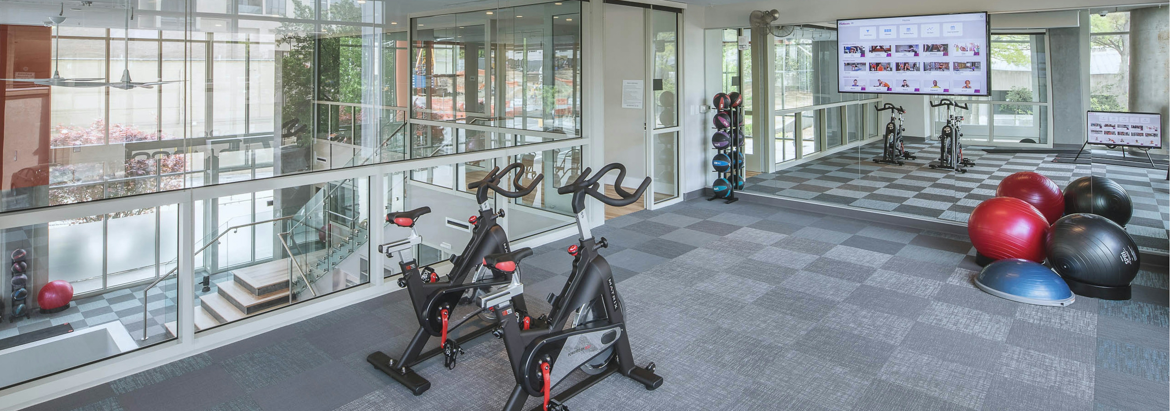 Fitness center at AMLI Arts Center with exercise balls and large wall mirror with glass walls overlooking downstairs area