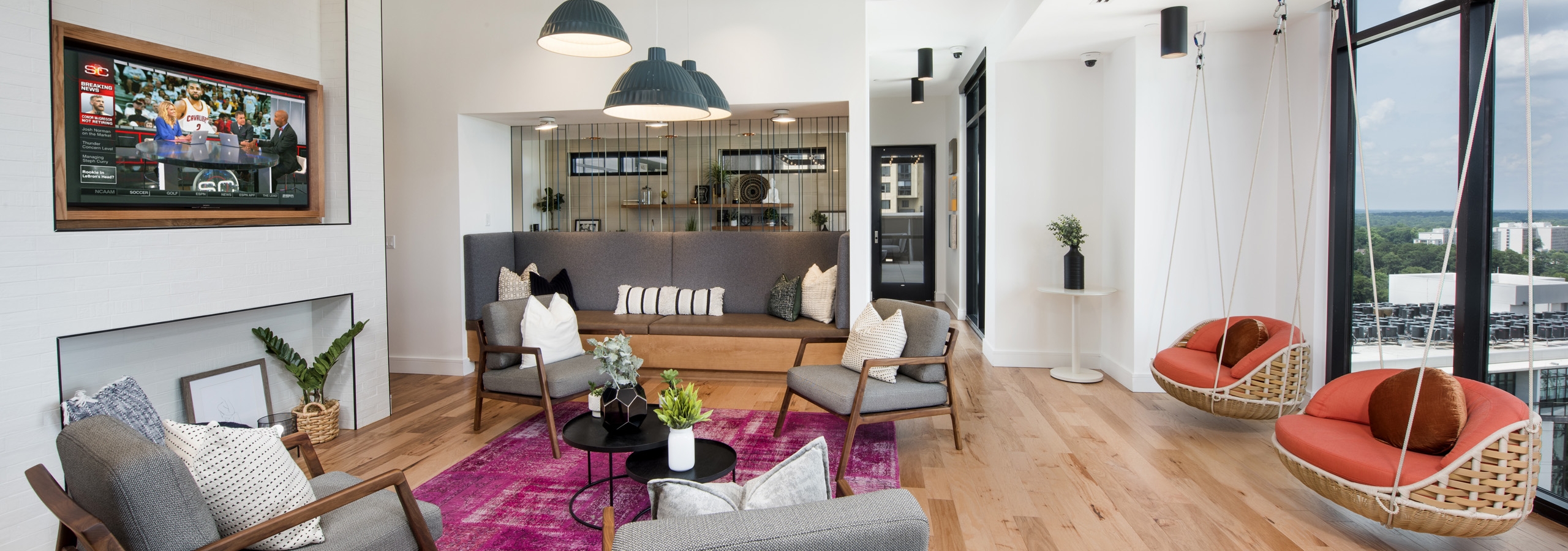 AMLI Lenox sky lounge with bright pink rug and multiple seating areas and a TV and two swings near large windows