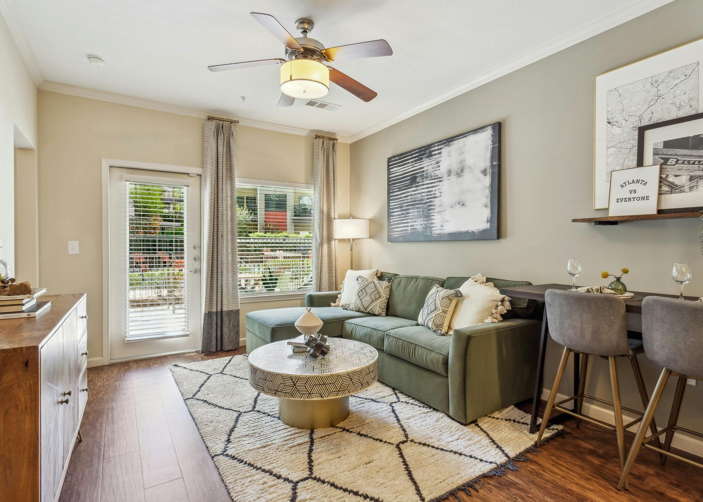 Living room at AMLI Ponce Park apartments with green couch on geometric area rug with windows with blinds and curtains