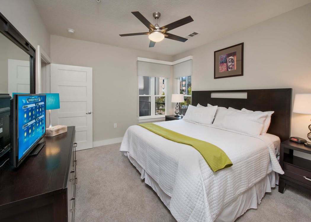 Interior of AMLI Piedmont Heights bedroom with grey walls and carpet with white bedding and windows to let in natural light