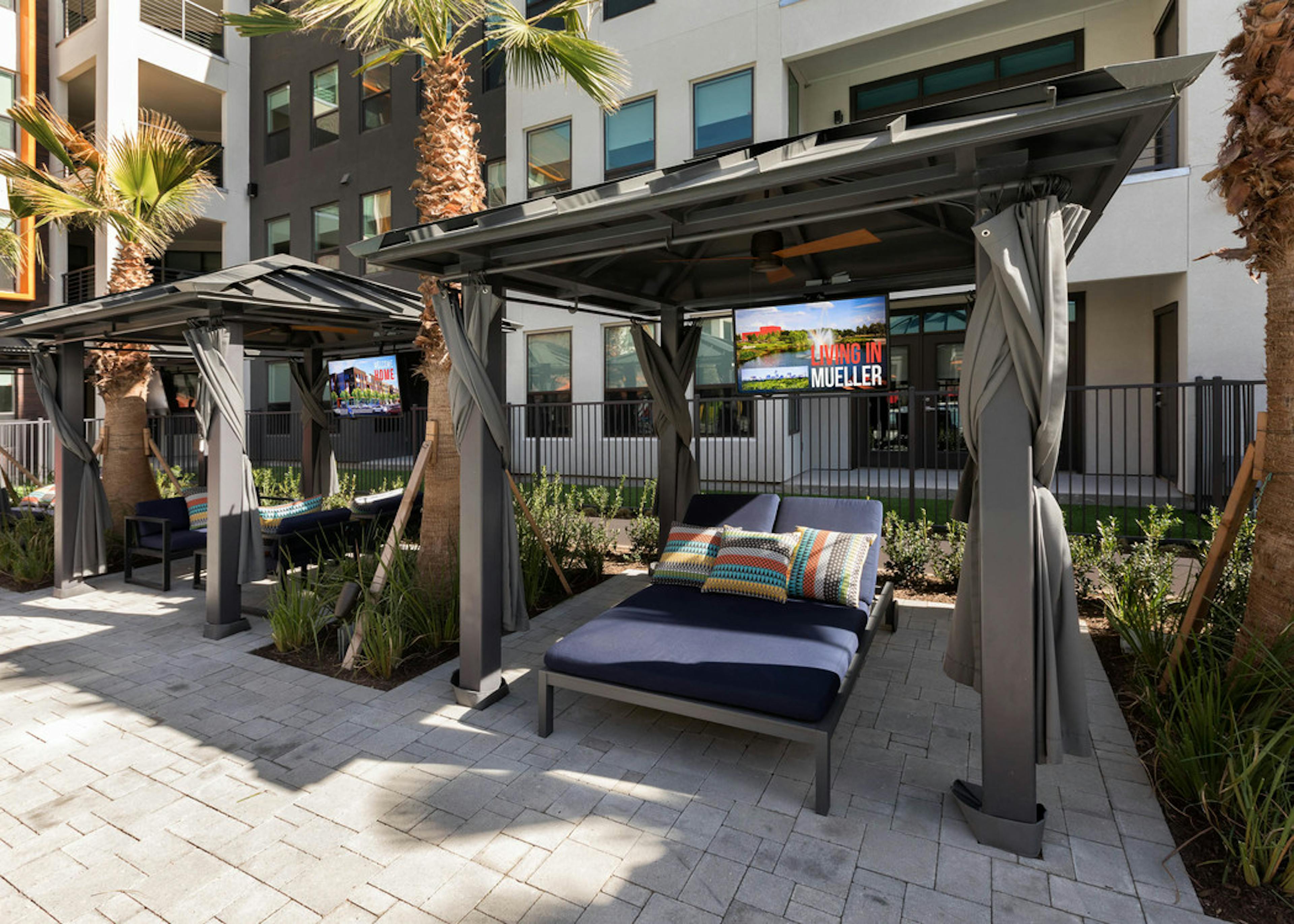 Close up of AMLI on Aldrich private poolside outdoor cabanas with individual TVs surrounded by palm trees