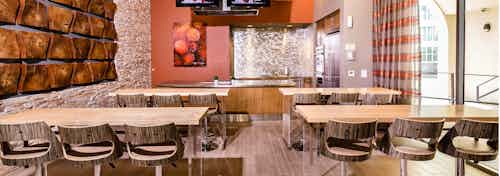 Interior of AMLI RidgeGate demonstration kitchen with 2 high mount TV's, stainless steel countertop and backsplash over sink