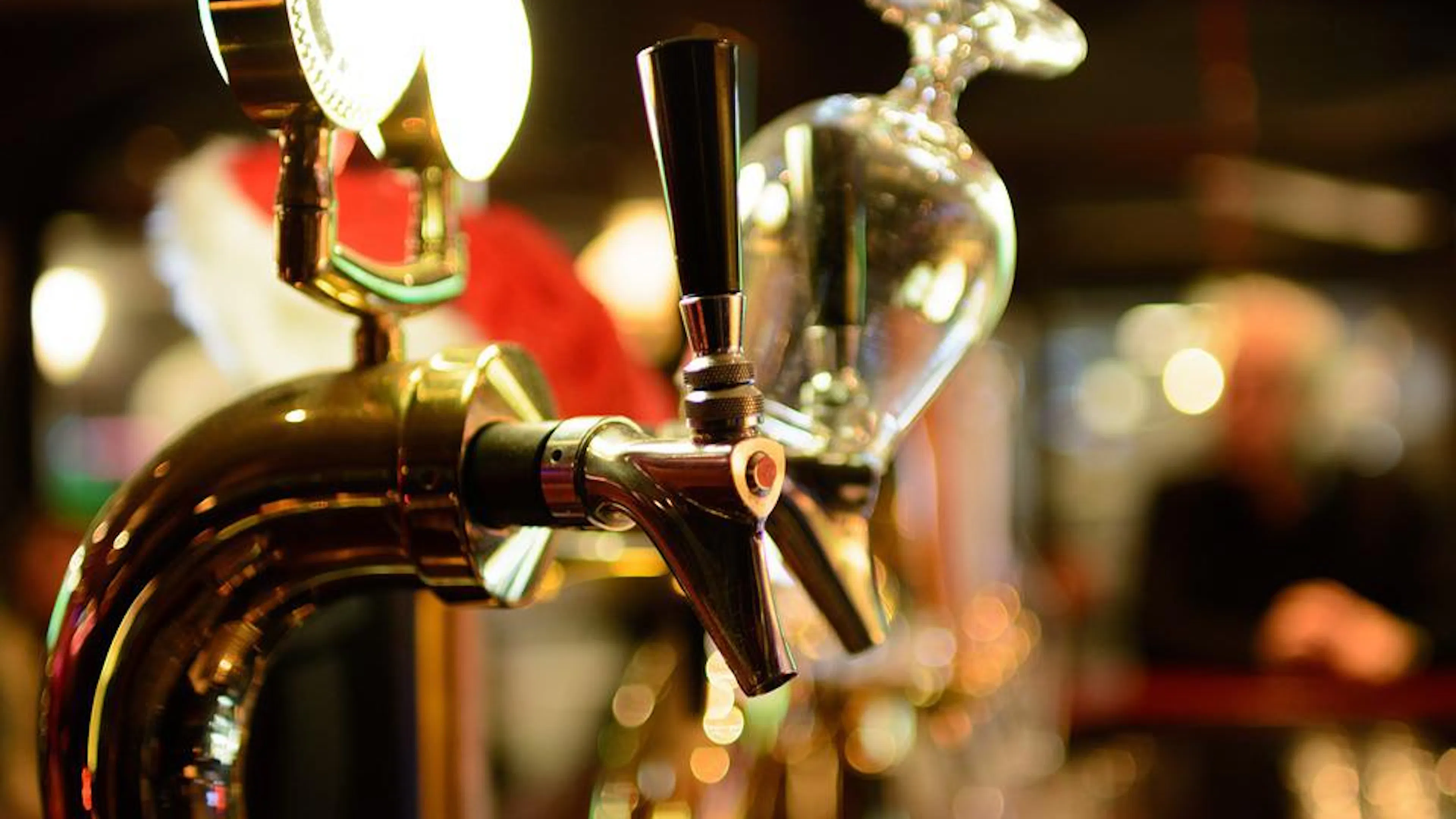 A beer tap close up with some empty glasses in the background