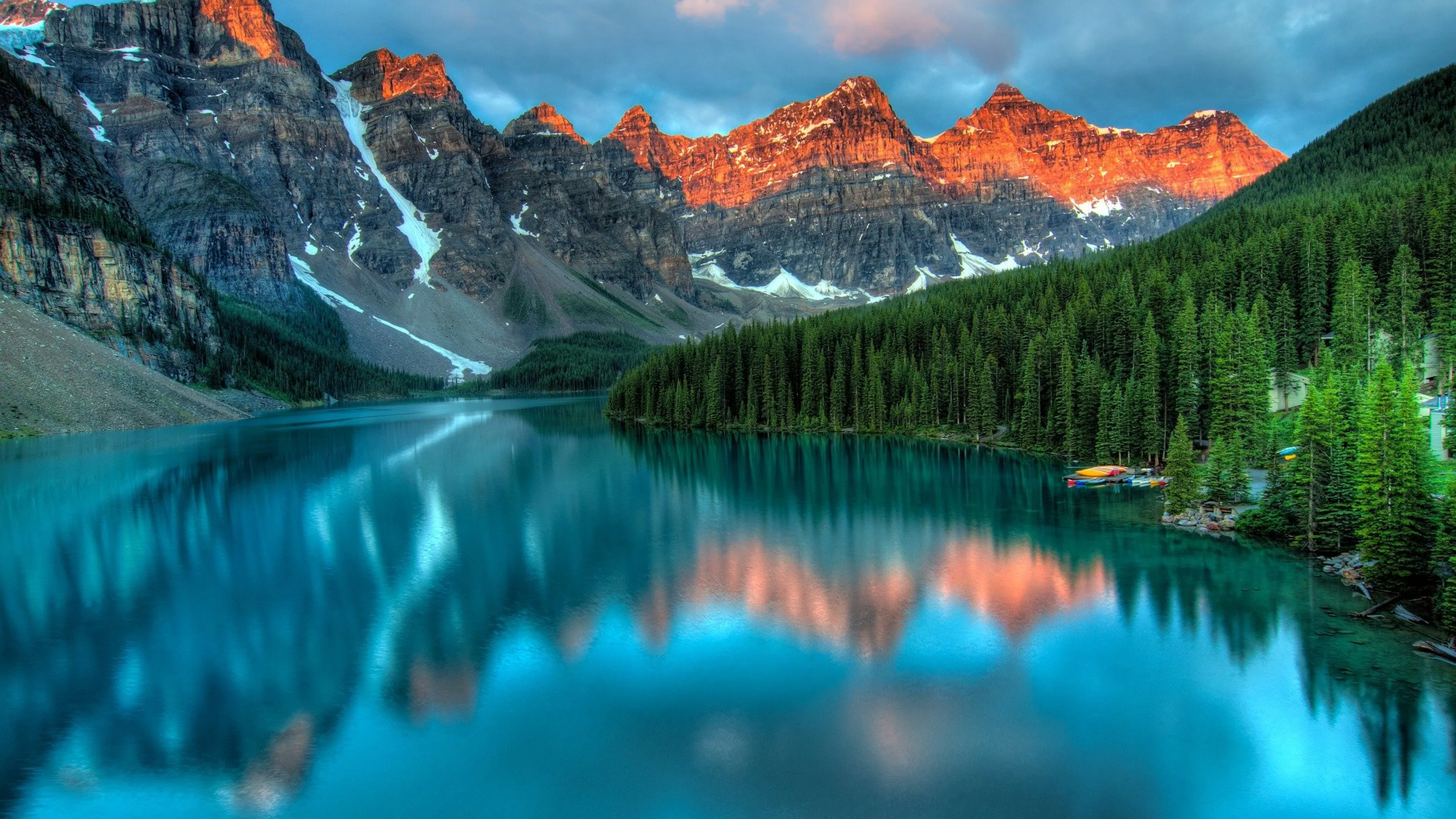 Snowy peaks behind a crystal clear lake and bright green pine trees on the shore