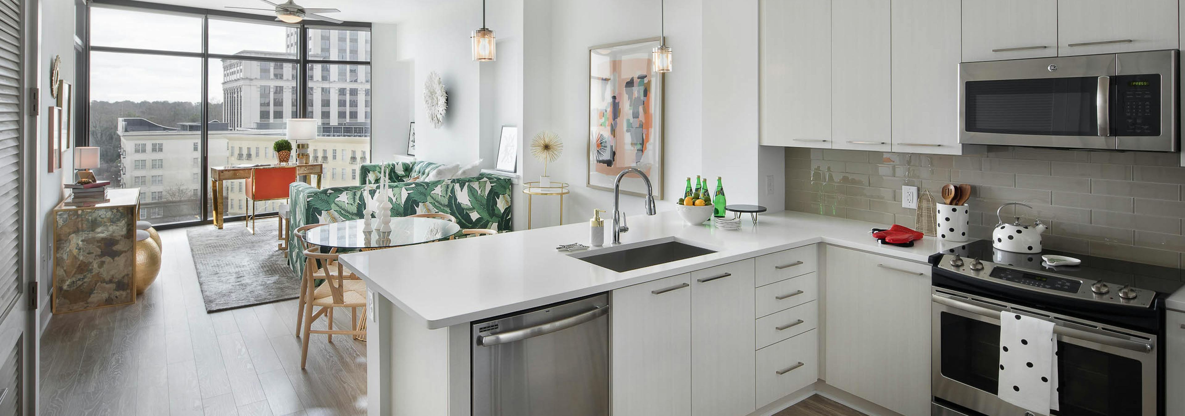 AMLI 3464 kitchen with white cabinets and countertops and view of the living room with floor to ceiling windows