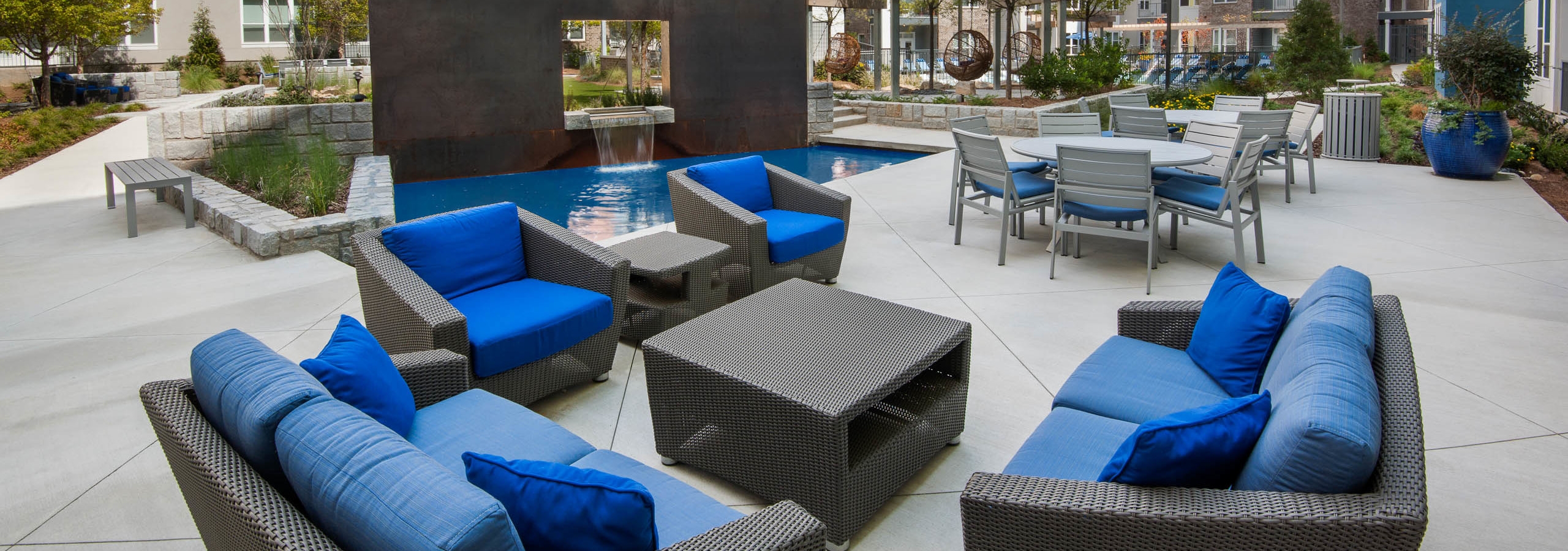 Daytime exterior view of sitting area in AMLI Piedmont Heights courtyard showcasing small and cozy couches with blue cushions
