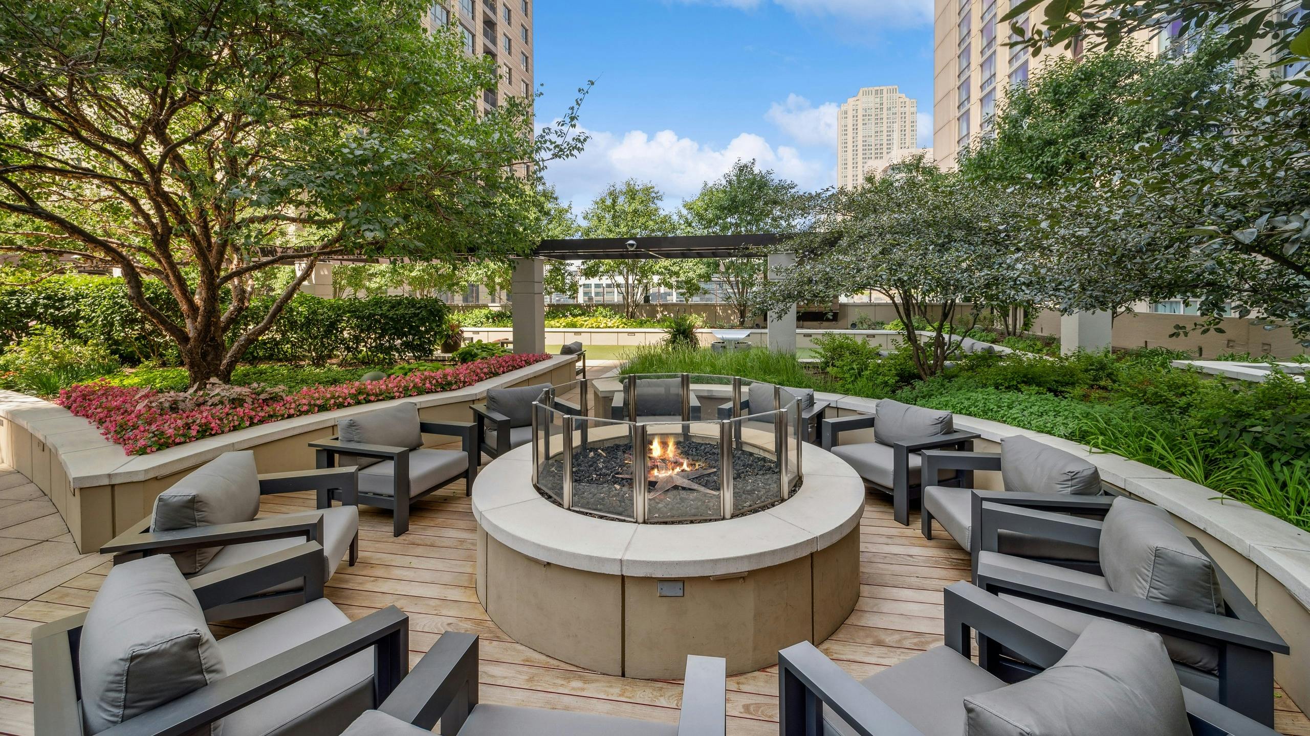 Rooftop firepit at AMLI River North with surrounding green foliage and gray chairs centered around a firepit with a flame