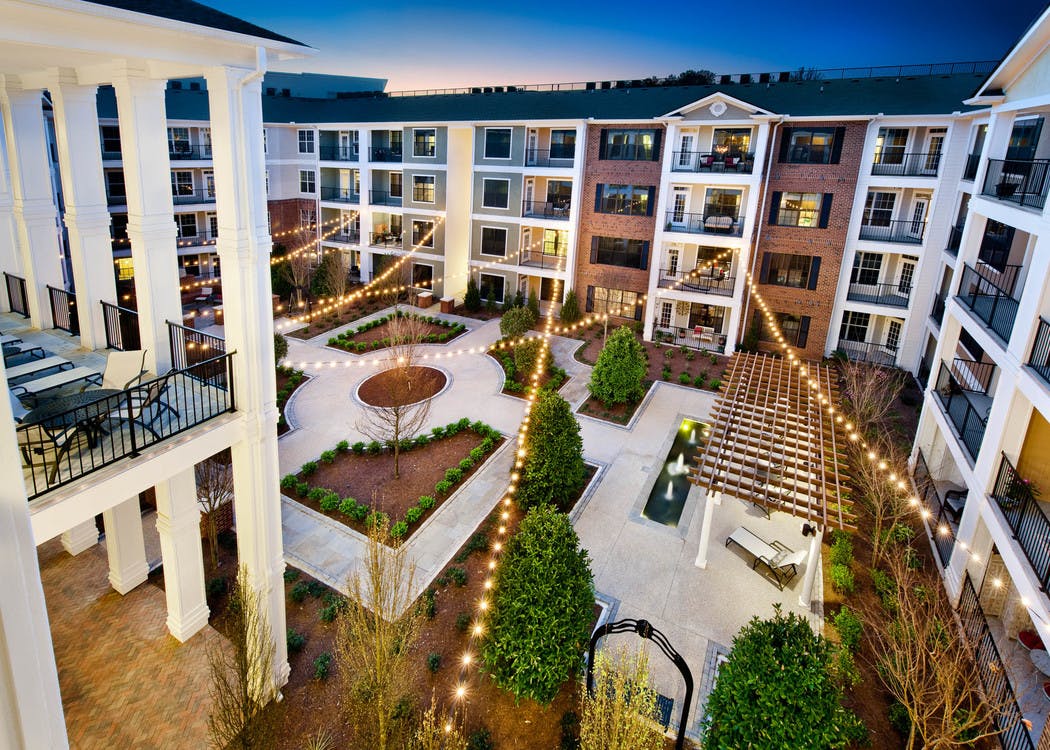 AMLI North Point courtyard with balconies and string lights above pavement for walking which is lined with pristine landscape