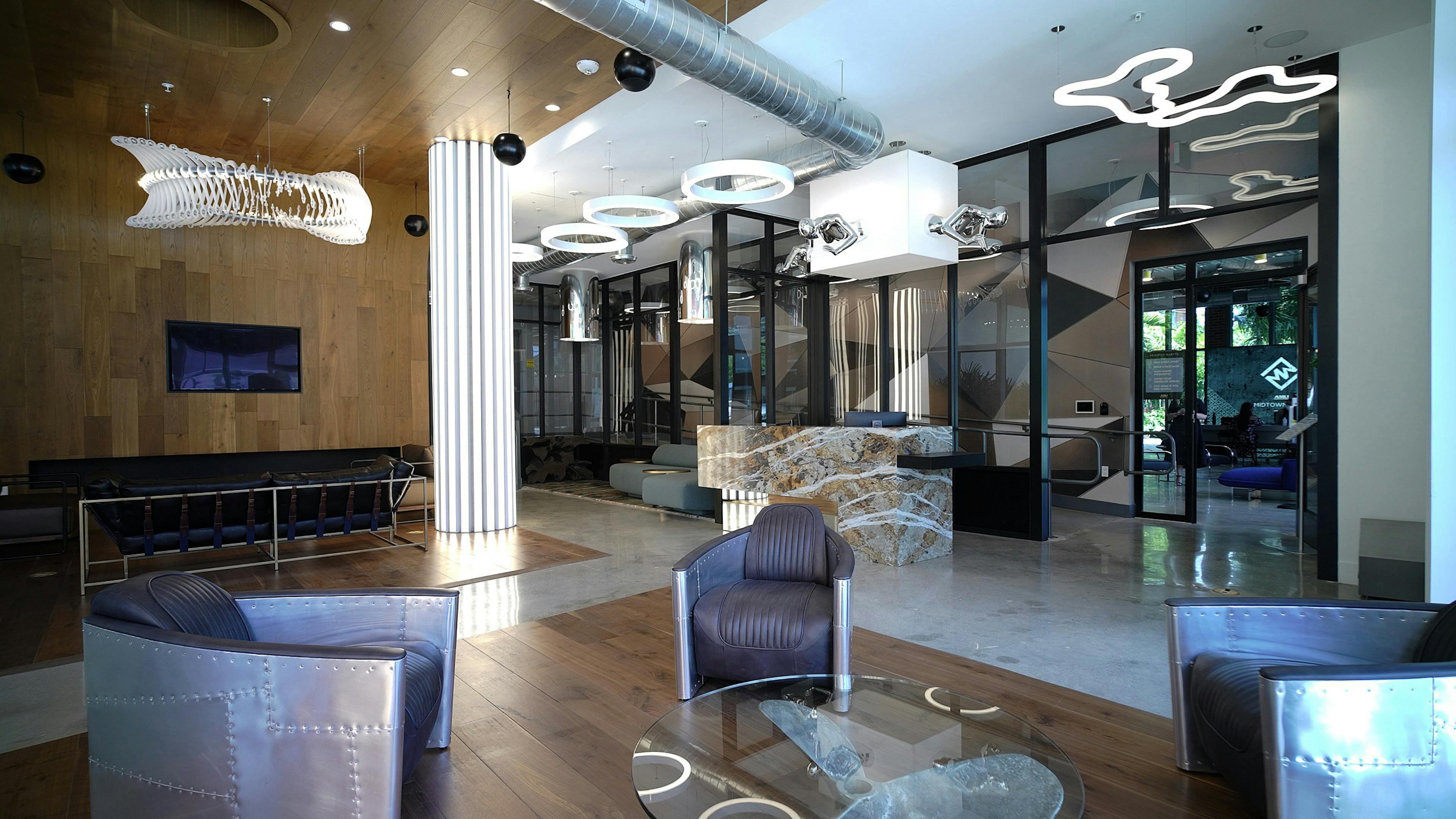 Lobby at AMLI Midtown Miami apartments with leather and metal chairs and modern light sculptures and marble and wood floors