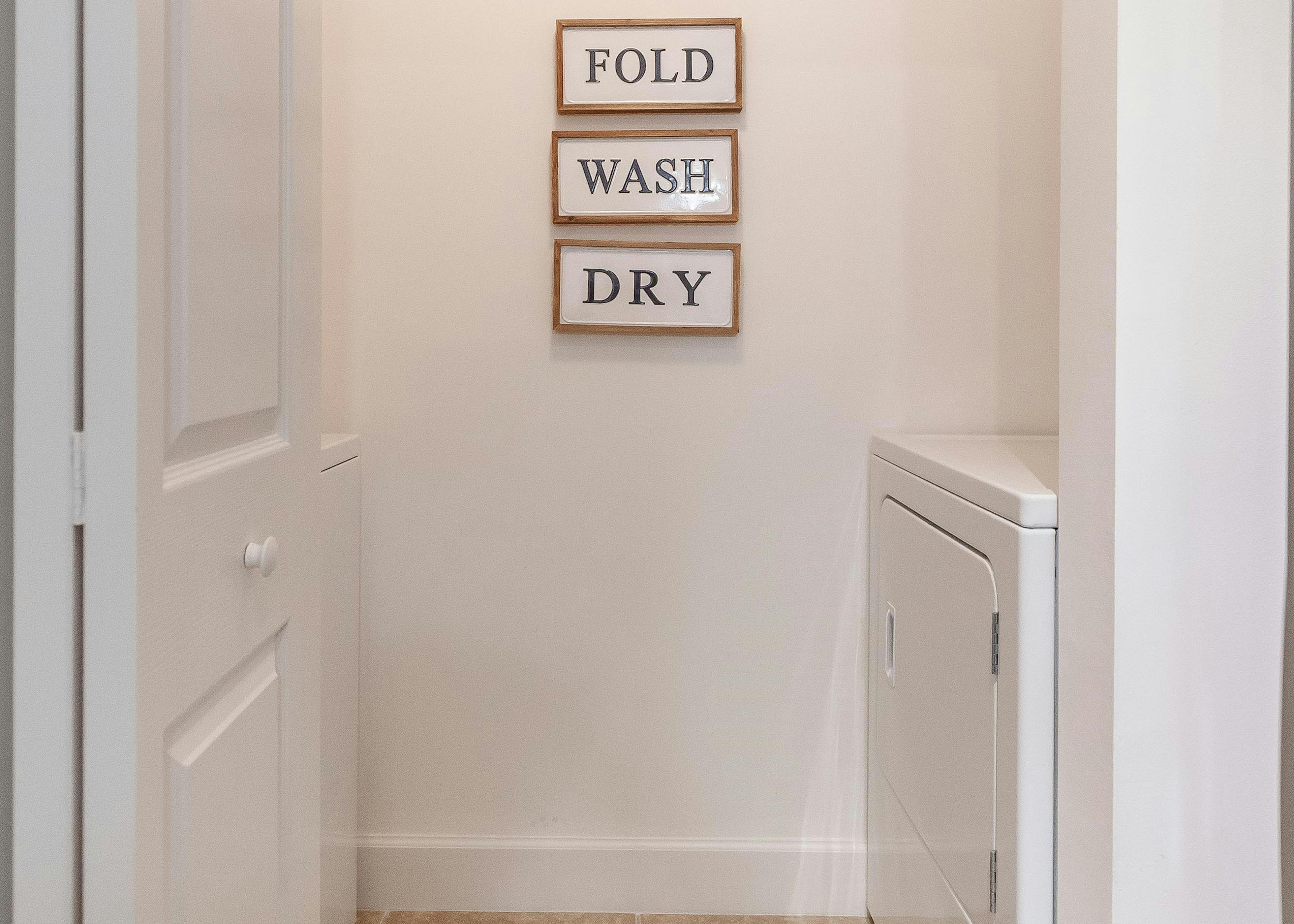 AMLI Toscana apartment laundry room with full size washer and dryer and fold wash dry artwork on wall and open closet door