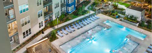 Aeriel view of AMLI Piedmont Heights pool featuring in water ledge loungers framed by lounge chairs and luscious landscape