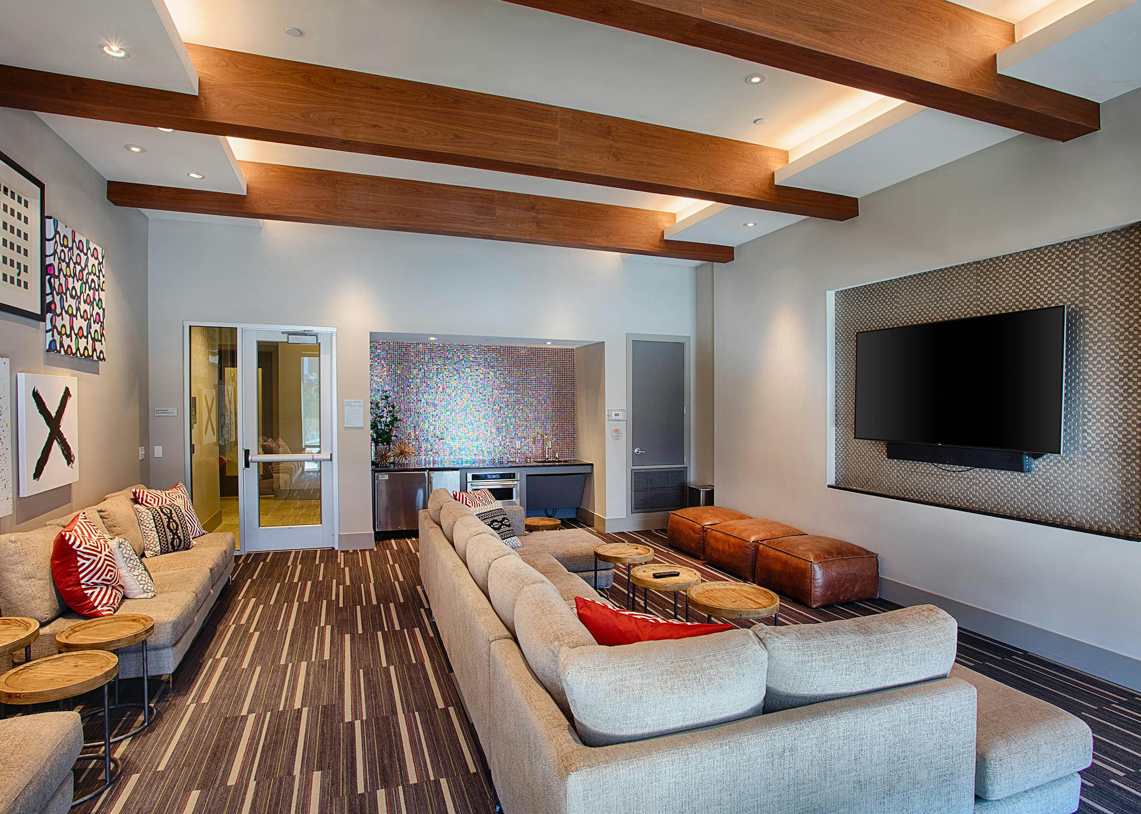 Interior view of the media room at AMLI Denargo Market apartments with large couches a small fridge and large television 