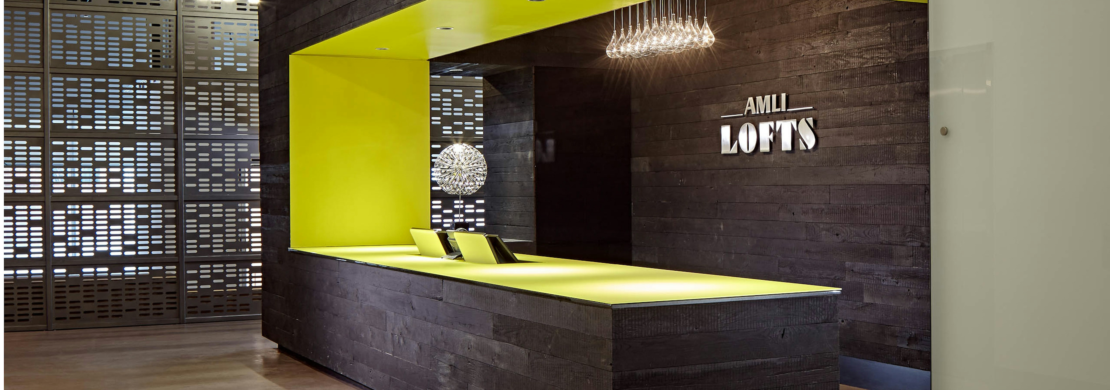 The Polk lobby at AMLI Lofts which has a deep brown textured accent wall and matching desk that has a vibrant yellow lining