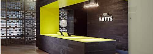 The Polk lobby at AMLI Lofts which has a deep brown textured accent wall and matching desk that has a vibrant yellow lining