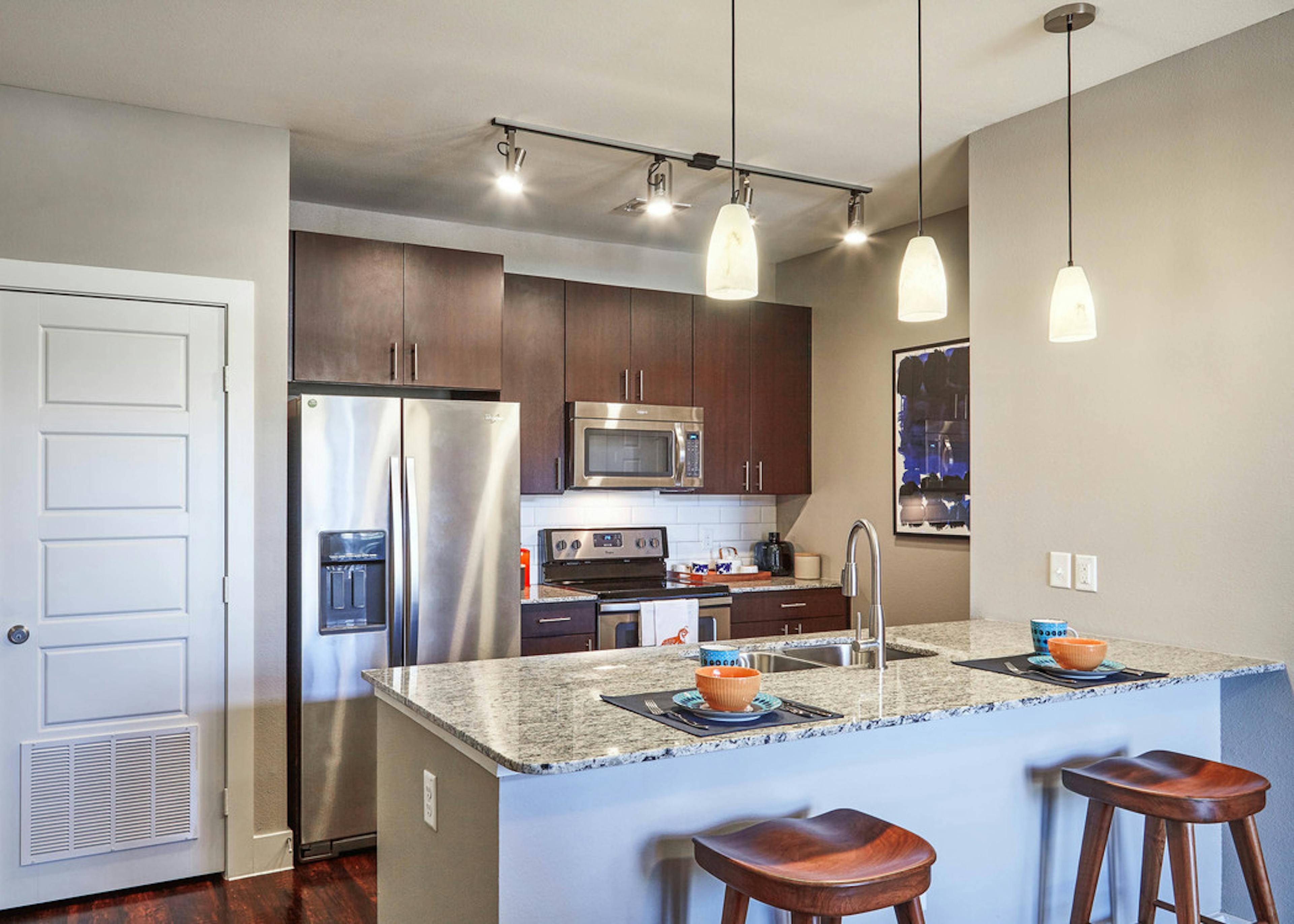 AMLI Covered Bridge gourmet kitchen with light walls, stainless steel appliances and under mount extra deep stainless sink