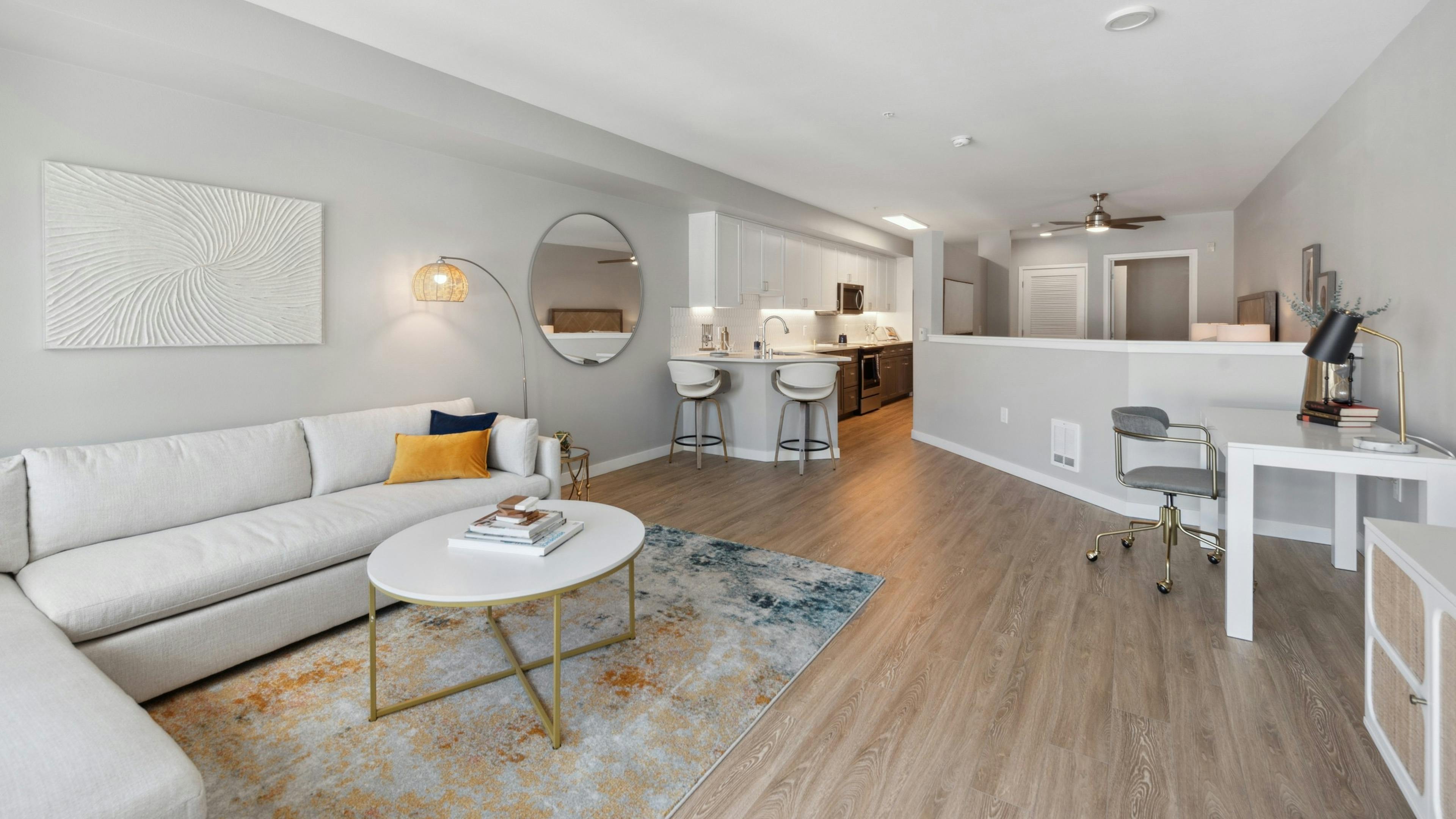 Living room with white couch and round coffee table with  view into kitchen and half wall to bedroom at AMLI 535 apartments