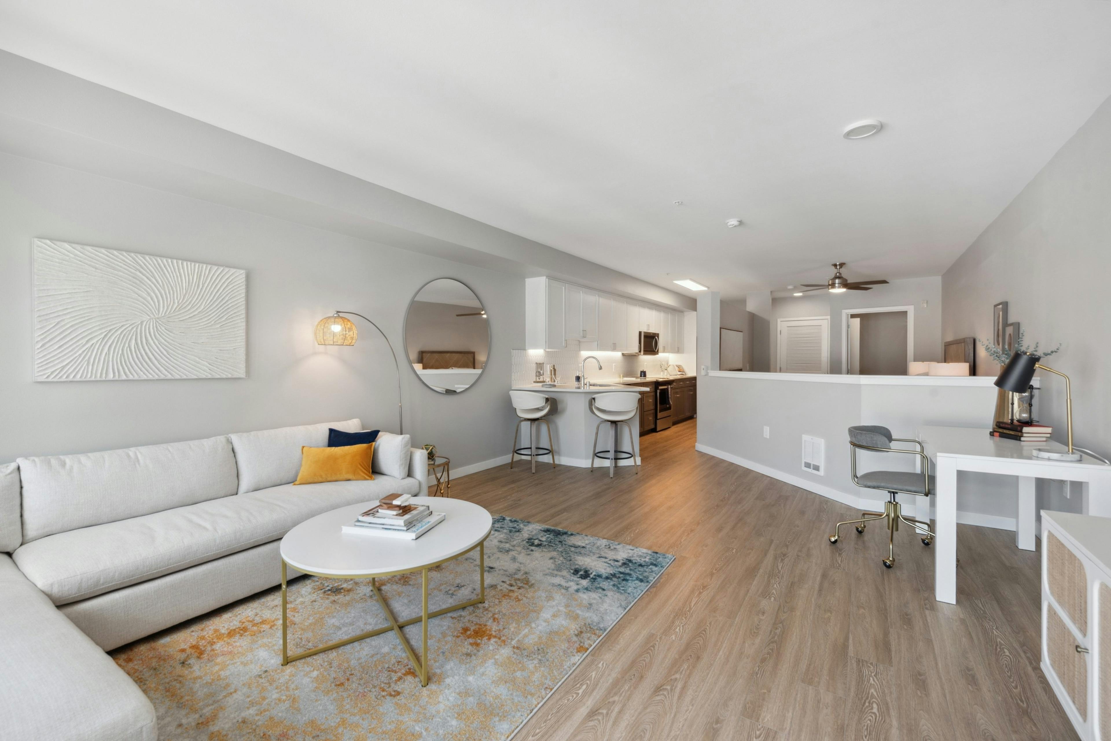 Living room with white couch and round coffee table with  view into kitchen and half wall to bedroom at AMLI 535 apartments